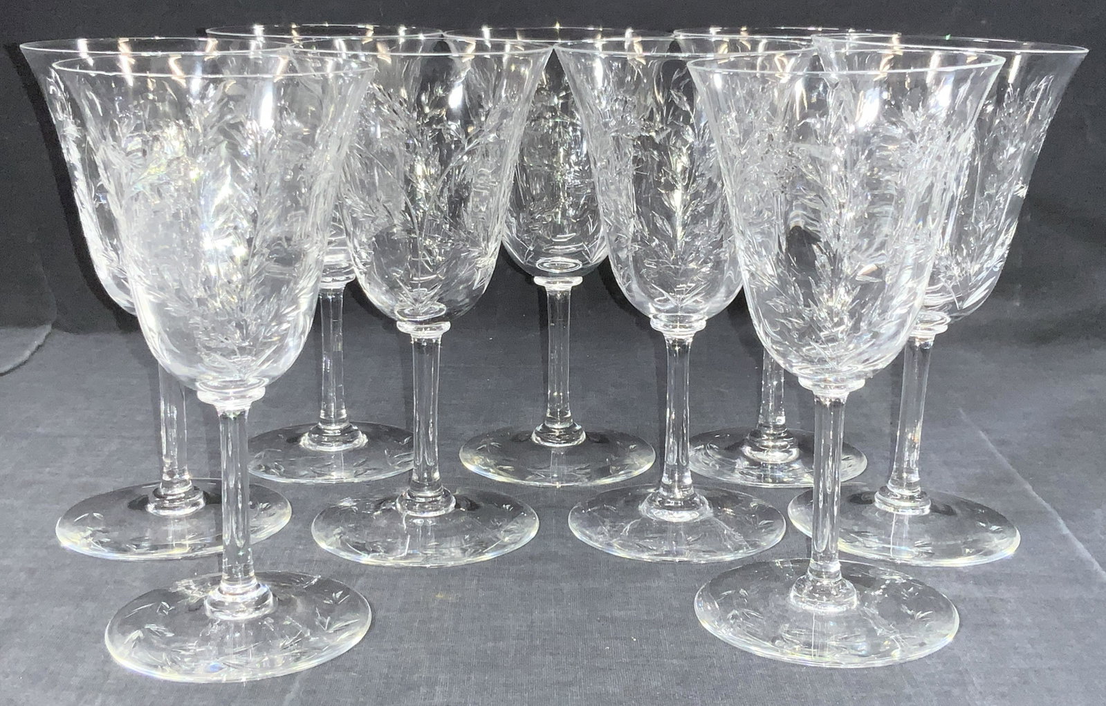 9 Vintage Etched Stemware Glasses: A set of 9 vintage etched stemware glasses with etchings of flowers and leaves on cups and on base. Approximately 6.5 inches tall. Slight chipping to rims. Etched glassware, glass stemware, wine glass