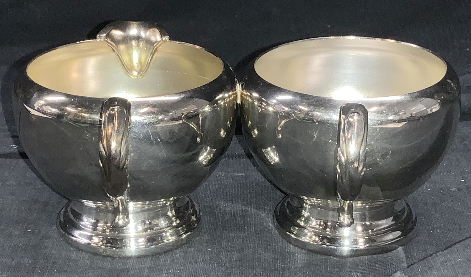WM Rogers Silver Tn Creamer and Cup, Signed: Silver tone footed creamer and tea cup, possibly sterling silver plated or nickel plate. A Paul Revere Style footed base. Signed on verso WM A Rogers. Creamer measures 5 x 2.5 in. Both have 2.75 in. d