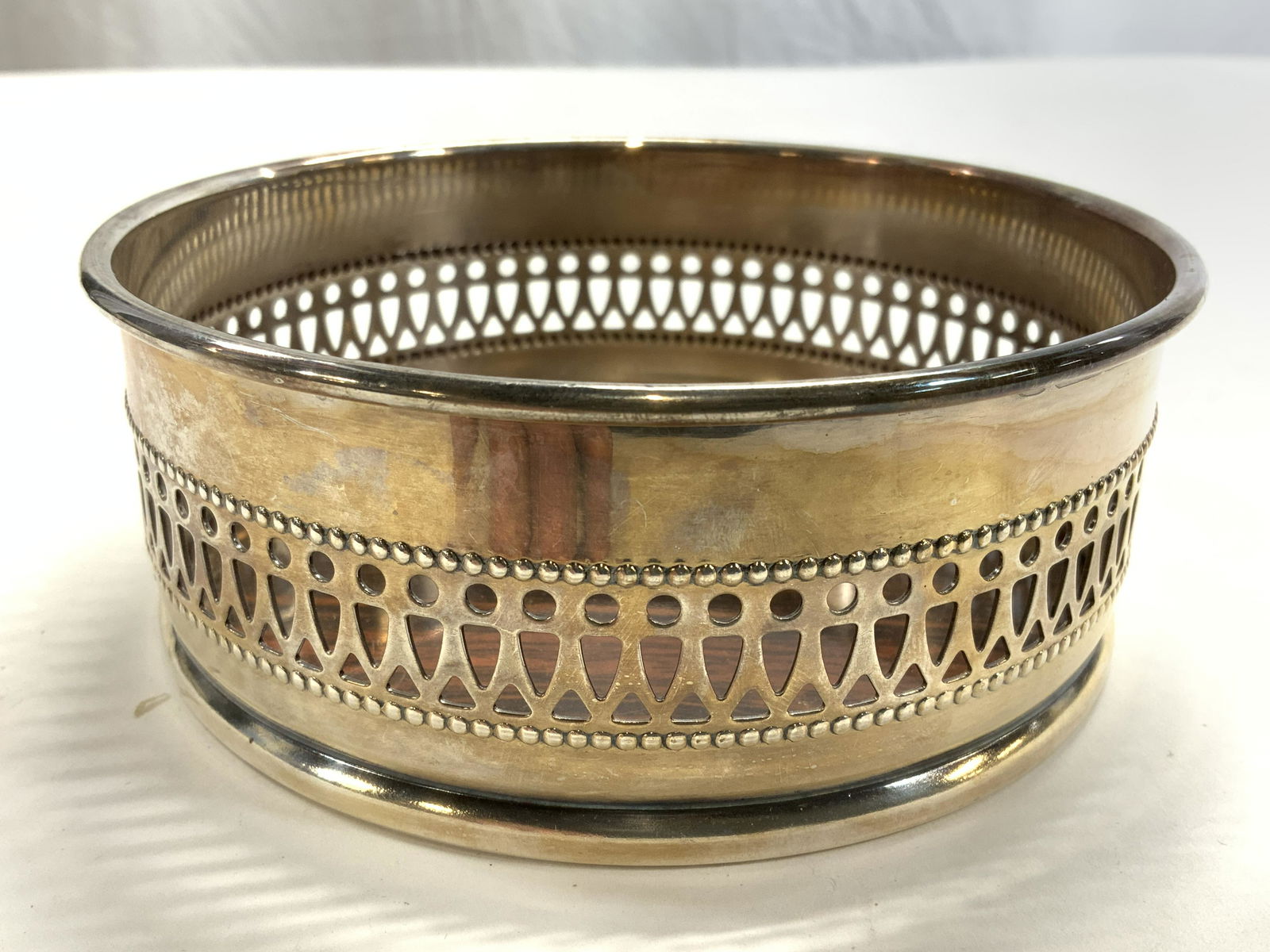 THE SHEFFIELD SILVER Silver Plated Formica Coaster: Underside has tag which reads THE SHEFFIELD SILVER,ADE IN USA FORMICA BRAND LAMINATE. Wine coaster is silver plated. Piece is circular shaped, and has walls with pierced geometric detail. Coaster meas