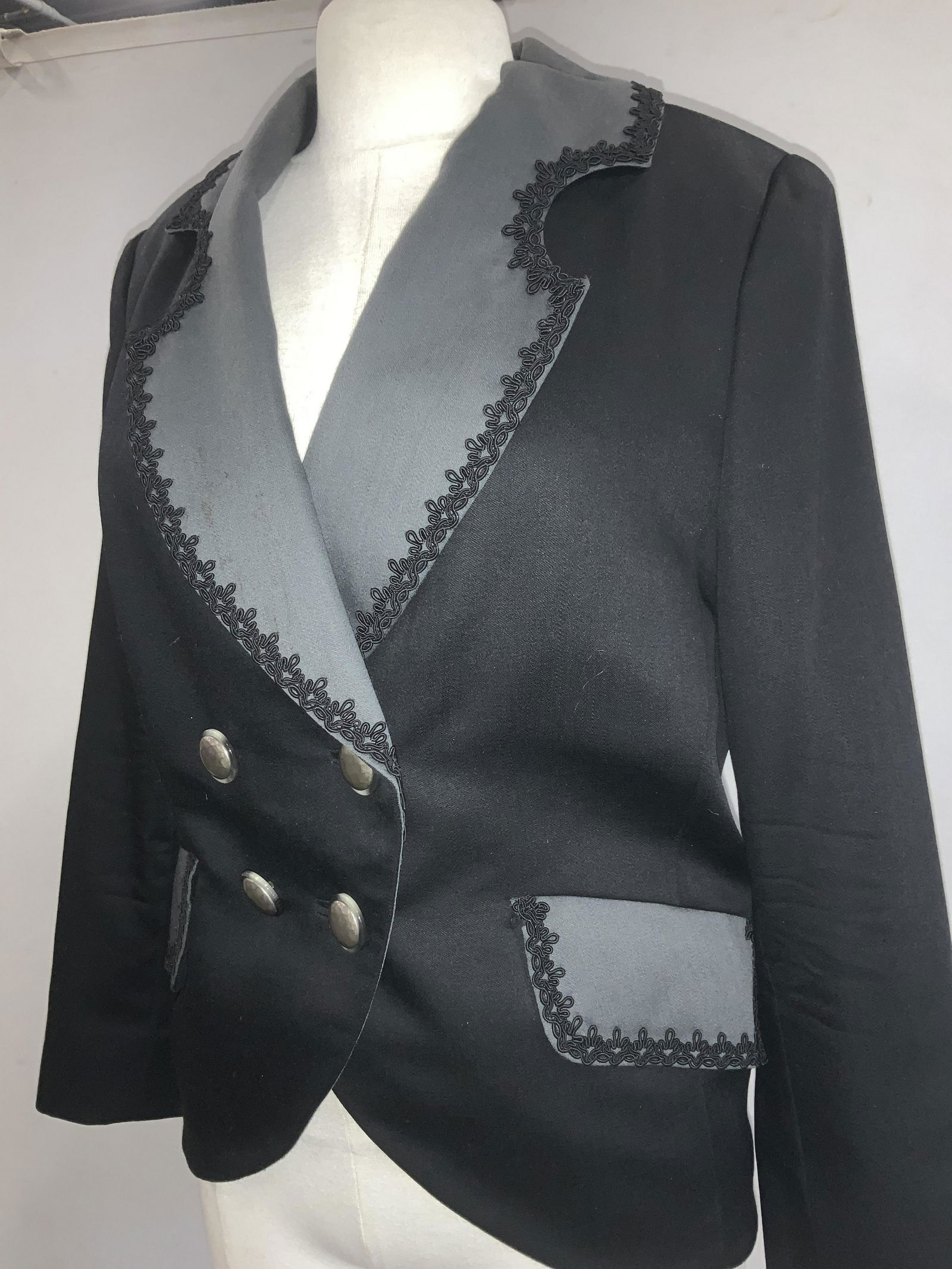 Custom Made Black Cocktail Blazer: Custom made black blazer, soft hand exterior and interior lining. Fabric unknown. Attractive shawl collar and pockets in a dark grey to give contract with decorative embroidered hems. Hand pockets, do
