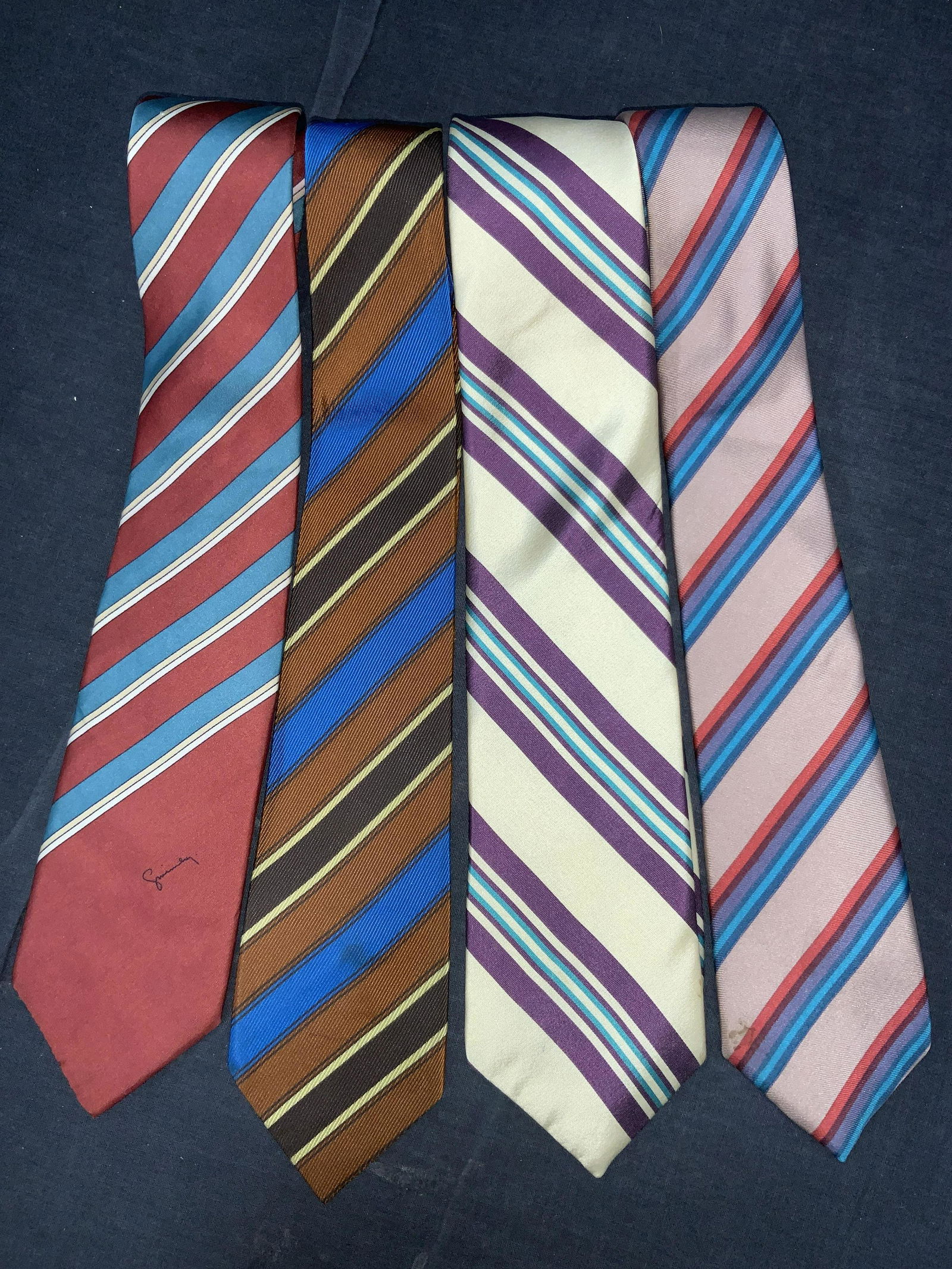 GIVENCHY, Ron Chereskin & More Silk Ties: A group lot of 4 striped ties. 1 orange and blue diagonal striped tie, with no brand or material tag. 1 cream tone and purple tie, marked Silk and Great Design on tags, 1 tan tie with reds, blues and