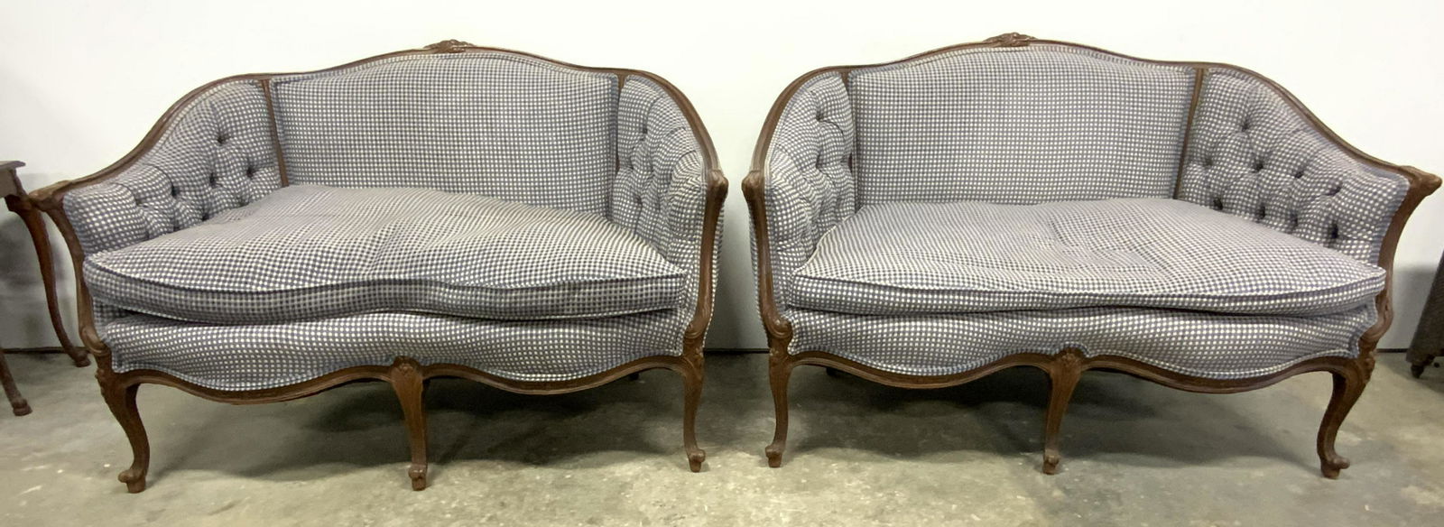 Pr Vintage Tufted Victorian Settee Sofas: Lot includes 2 sofas. Each are upholstered with checkered style detail. Sides of each backrest are tufted. Settees have intricately carved wooden frames with floral, leaf & scroll detail. Edges of uph