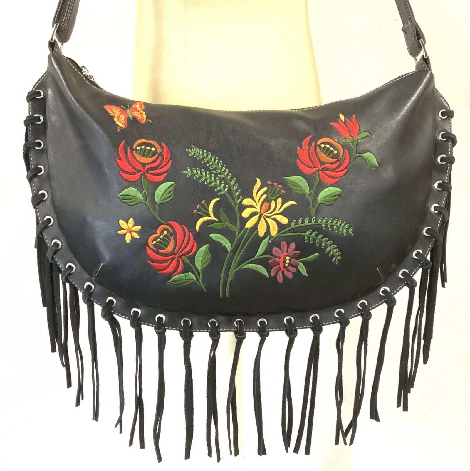 Boutique Black Leather Fringed Crossbody Bag: Boutique Black Leather Fringed Crossbody Bag, silver toned hardware, embroidered floral motif, single strap with adjustable length, exterior has one zipper pocket. Interior compartment has brown nylon