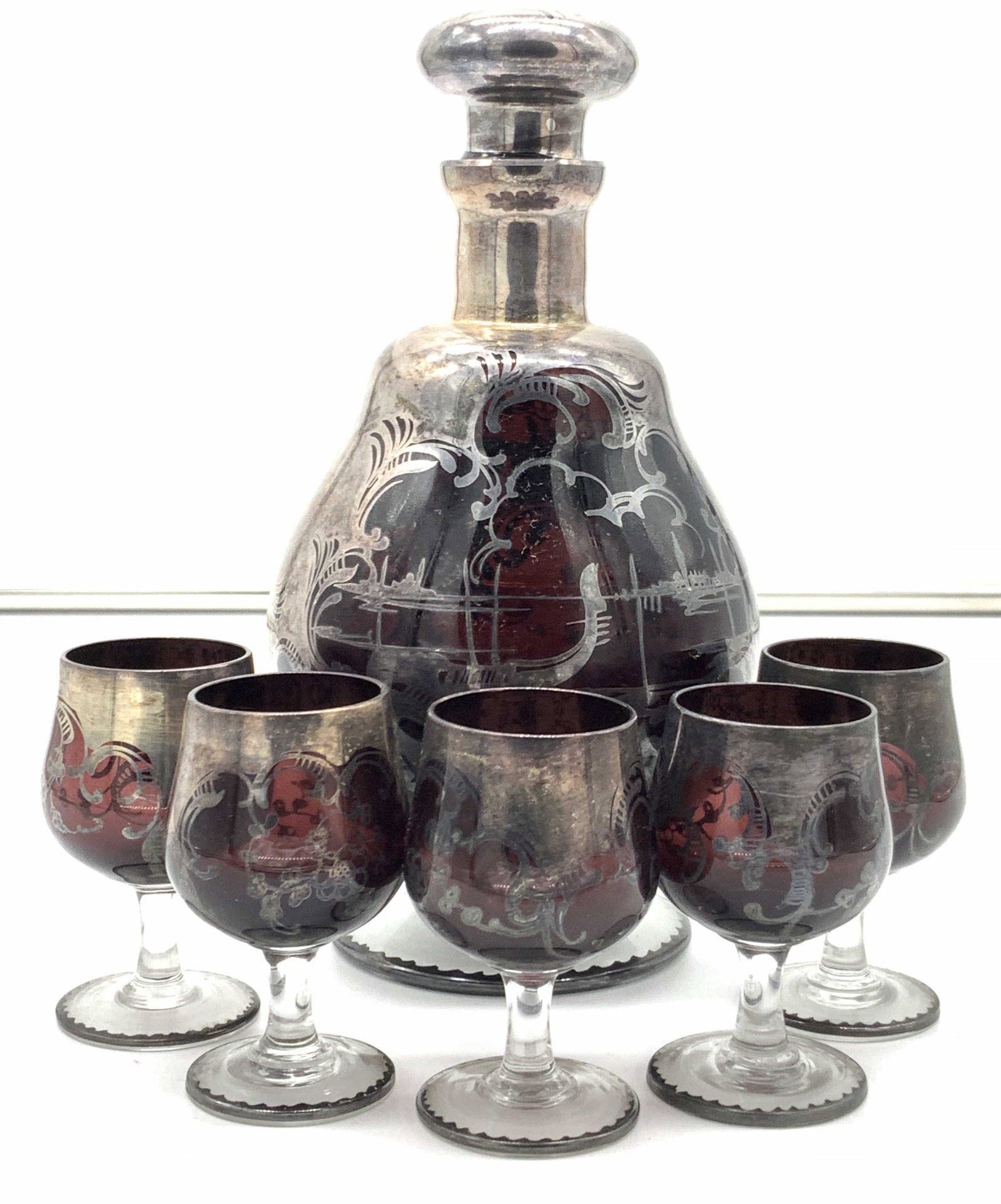 Vintage Hand Blown Art Nouveau Cranberry Barware: A set of shot glasses and decanter. Made of hand blown cranberry glass with art nouveau patterns in a silver toned over lay, possibly silver, possibly higher quality silver, no discernible hallmark. D