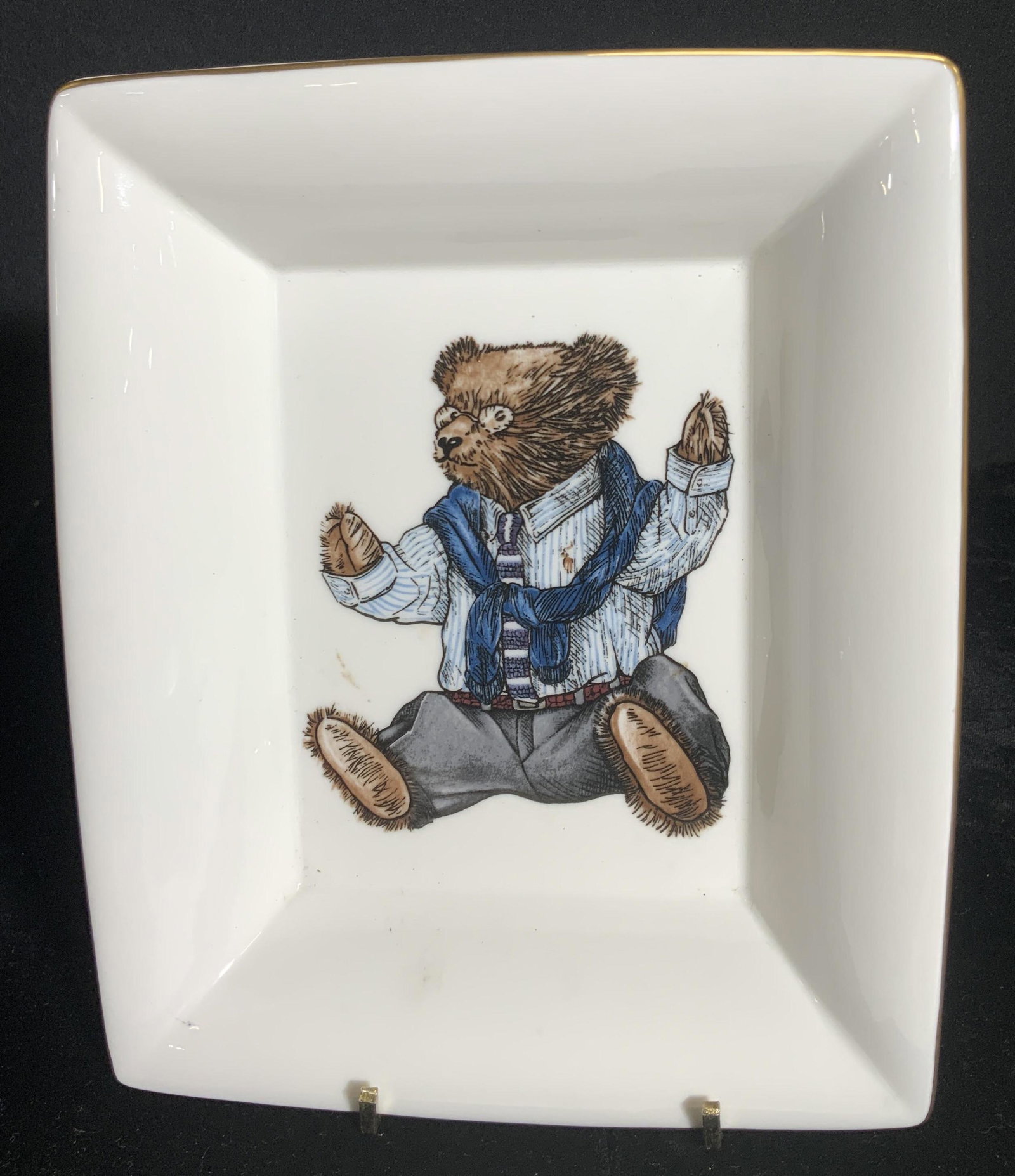 WEDGWOOD RALPH LAUREN POLO BEAR Porcelain Plate: A white square form plate with a well dressed bear to the center. Gilt rim. Reverse signed WEDGWOOD RALPH LAUREN POLO BEAR. Measures approx 1.25H x 8W in. Measured at widest point. Some surface wear t
