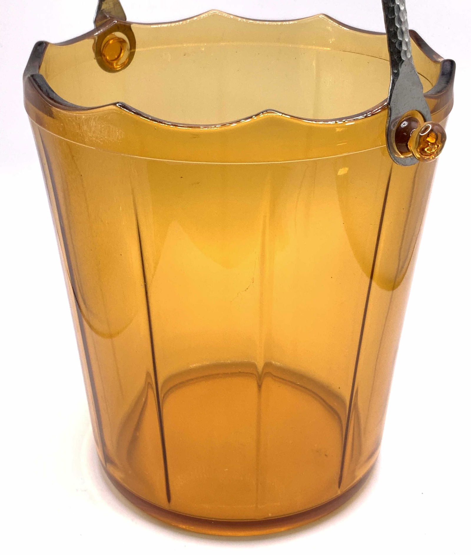 Vintage Amber Glass Handled Ice Bucket: A vintage amber glass ice bucket with a hammered silver tone metal top handle. Ribbed design to the glass. Saw tooth style rim. Measures approx 6H x 6W in. Some surface wear consistent with use and ag