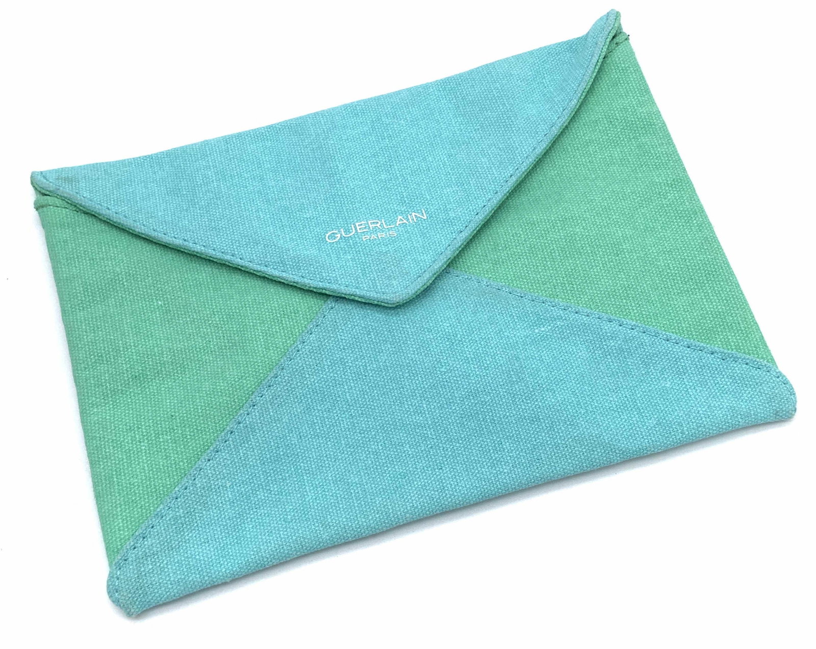 GUERLAIN PARIS Teal & Green Fabric Envelope Clutch: A teal blue and green hued envelope style clutch. Snap button closure. Obverse reads GUERLAIN PARIS. Measures approx 6L x 8W in. Some discoloration to piece, Property of Manhattan, New York Estate. We