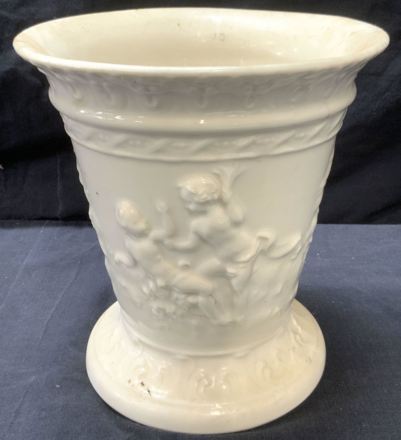 Von SCHIERHOLZ Signed Capri Pedestal Vase, GERMANY: Von SCHIERHOLZ Signed Capri Pedestal Vase, made in Germany, white porcelain, rococo style relief with angels, verso reads Von Schierholz Capri Made in Germany. Measures approx 6 3/4 x 6 1/4 in. Proper