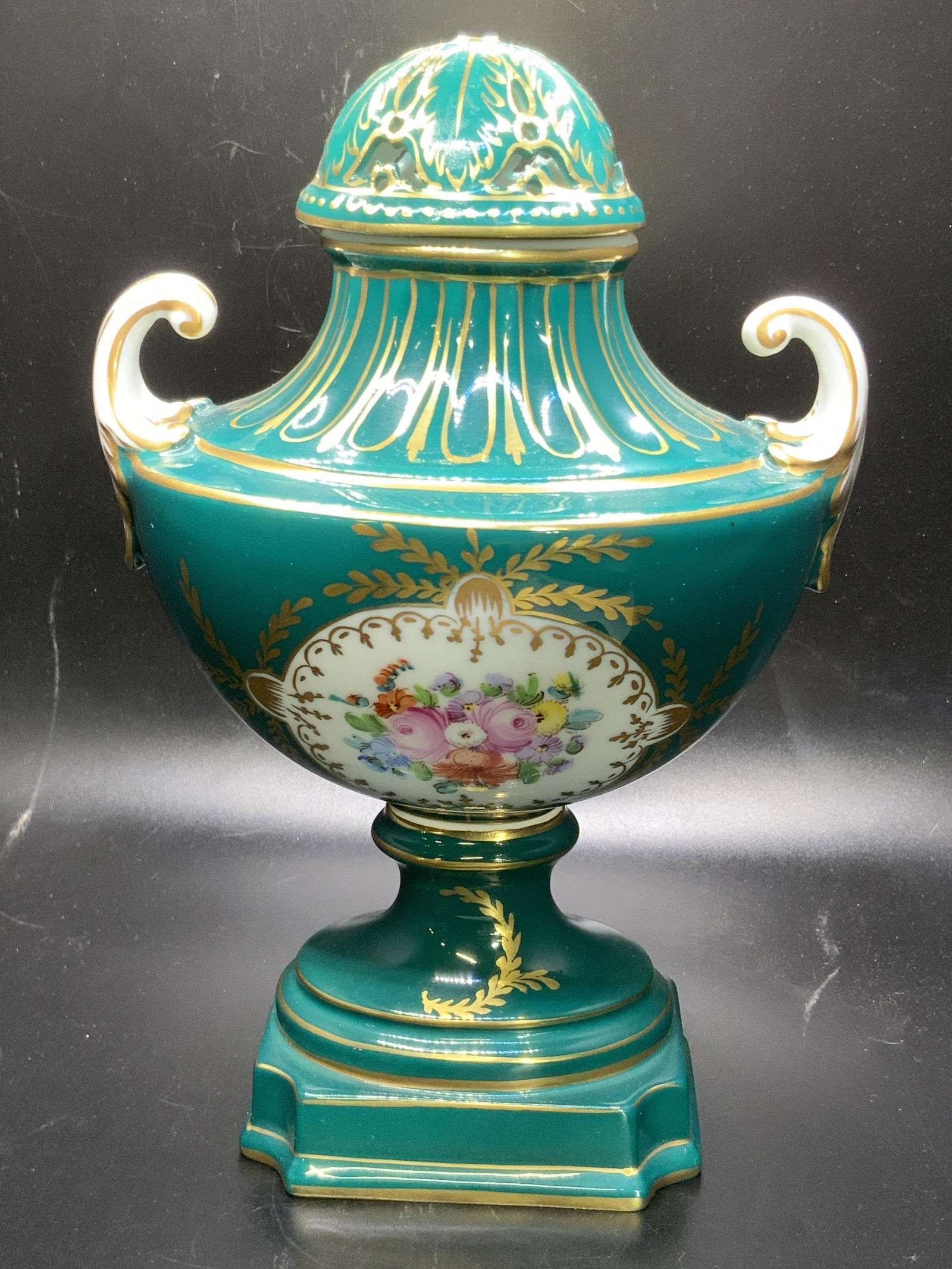 Trademarked Vintage Porcelain Lidded Urn Vessel: Vintage, possibly antique, hand painted porcelain lidded urn vessel. Primarily green, pink, blue, red, and purple hues alongside gilt line work and pierced porcelain detailing in the lid. Florals acce