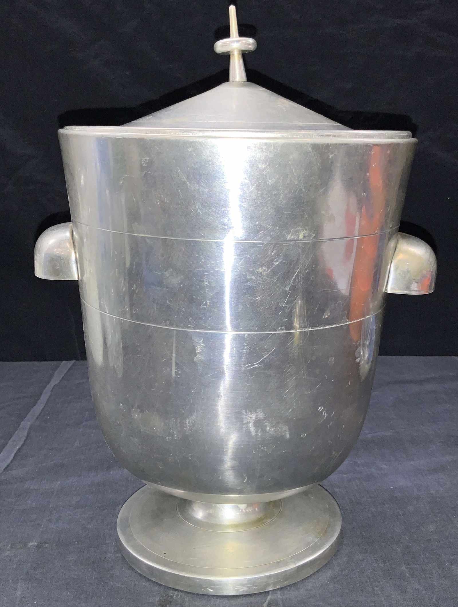 NASCO Composite Footed Ice bucket, Italy: Footed Ice bucket with lid, side handles, silver toned composite material, light weight. Marked on underside NASCO, Italy. Slight dents to lid. 7 1/2 in in diameter, handles add approx 1 in to each si