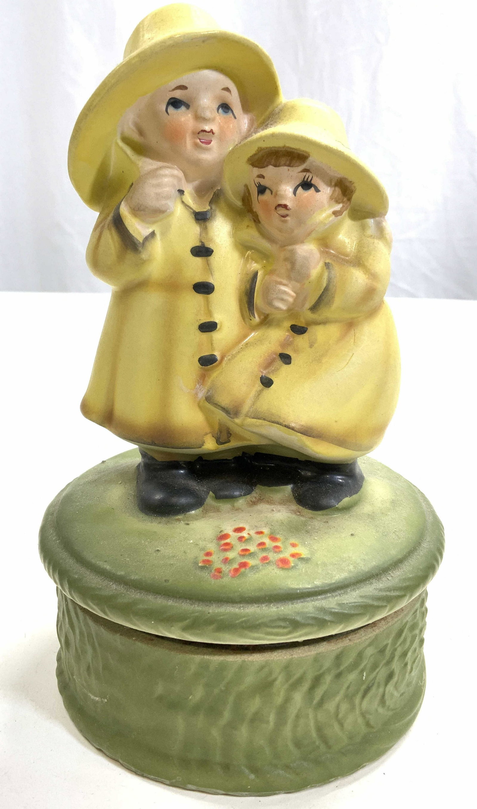 Vintage Porcelain Music Box W Child Figures: Music box is vintage and porcelain. Piece has 2 children figures wearing raincoats. Music box appears to be hand painted. Piece measures approx 7 inches tall 4.25 inches wide. Music box, vintage music