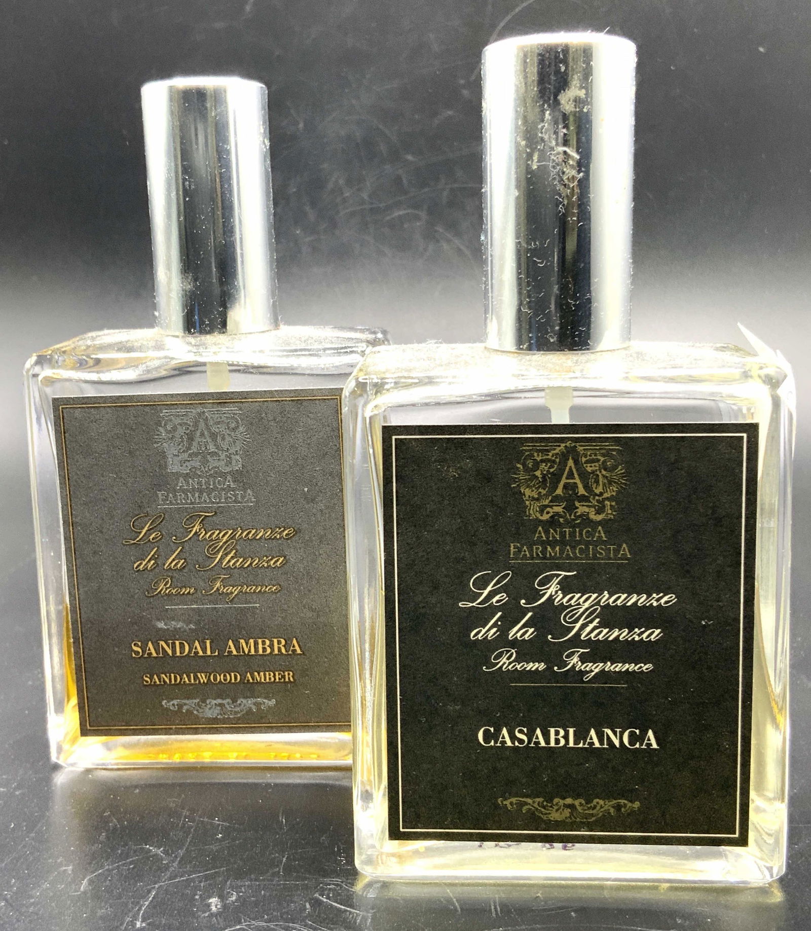 Antica Farmacista Sandal Ambra & Casablanca Perfum: 2 Perfumes from Antica Farmacista. Sandalwood amber and Casablanca. room fragrances. Both bottles are rectangular in shape with silver toned caps. Bottles are marked on underside Made in France. Parti
