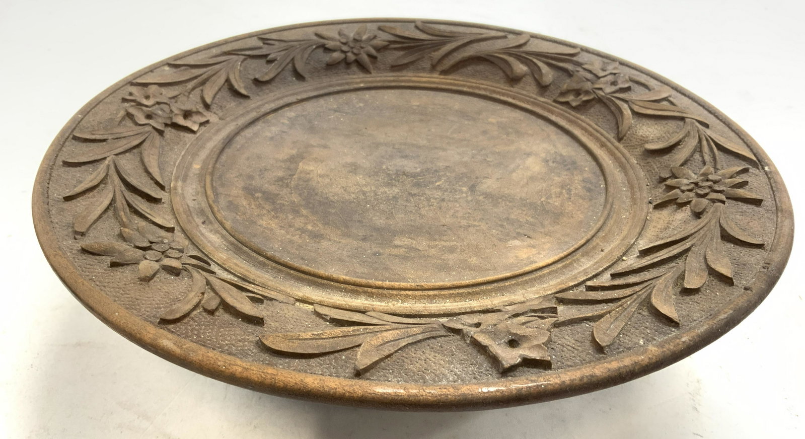 Vintage Carved Wooden Pedestal Music Box: Pedestal is vintage and wooden. Piece has carved floral and leaf detail around rim. Piece has 3 feet. Underside has twist metal crank. Piece measures approx 10 inches wide 3 inches tall. Pedestal, woo