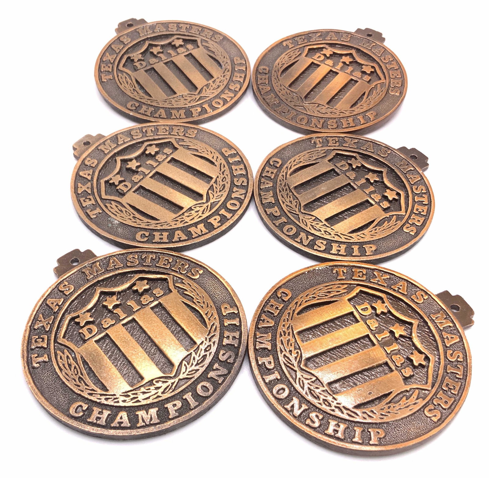 Lot 6 TEXAS MASTERS CHAMPIONSHIP Medals: Six TEXAS MASTERS CHAMPIONSHIP Medals crafted from deep copper toned metal. Possibly copper. Etched and raised metalwork. Bails to the top. Crafted from weighty metal material. Measures approx 2.5L x 