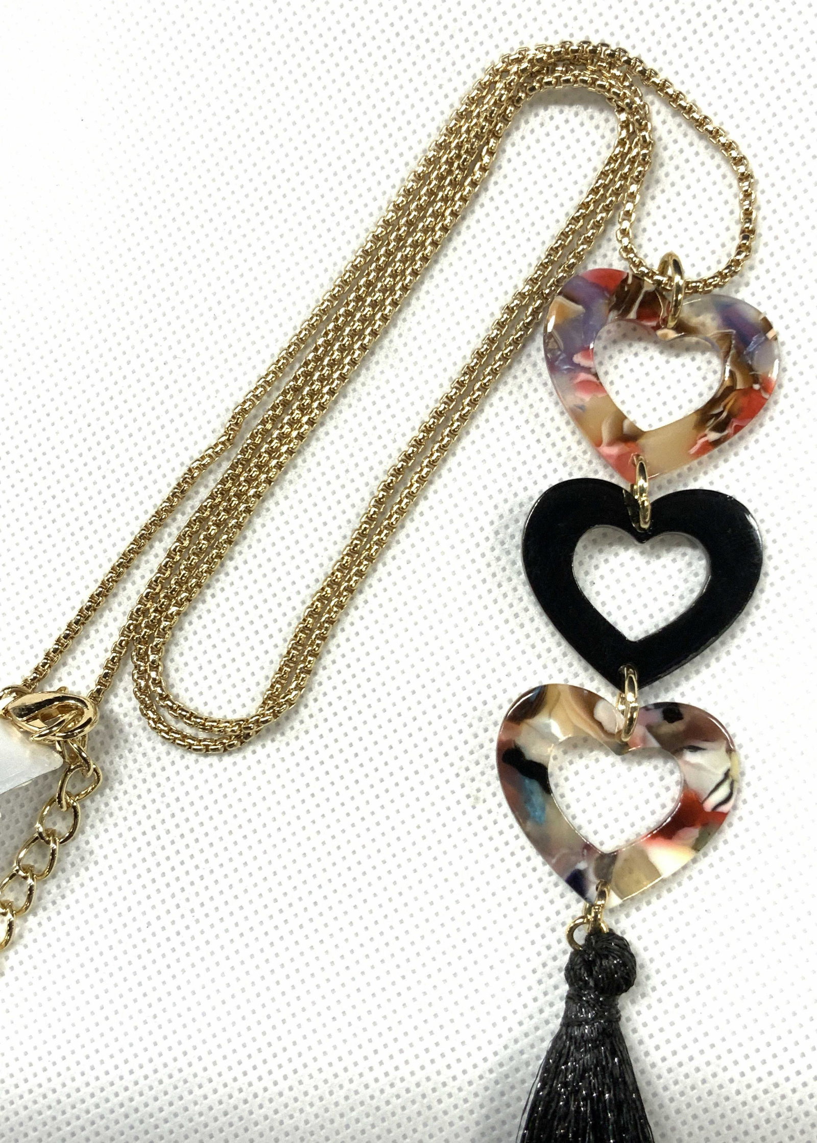 INC Signed Heart Tassel Opera Necklace: Opera length necklace with three resinous heart charms affixed to a black tassel. Marked INC on clasp charm. Approximately 22 - 25 inches long. Inc signed jewelry, tassel necklace, opera necklace, Fas