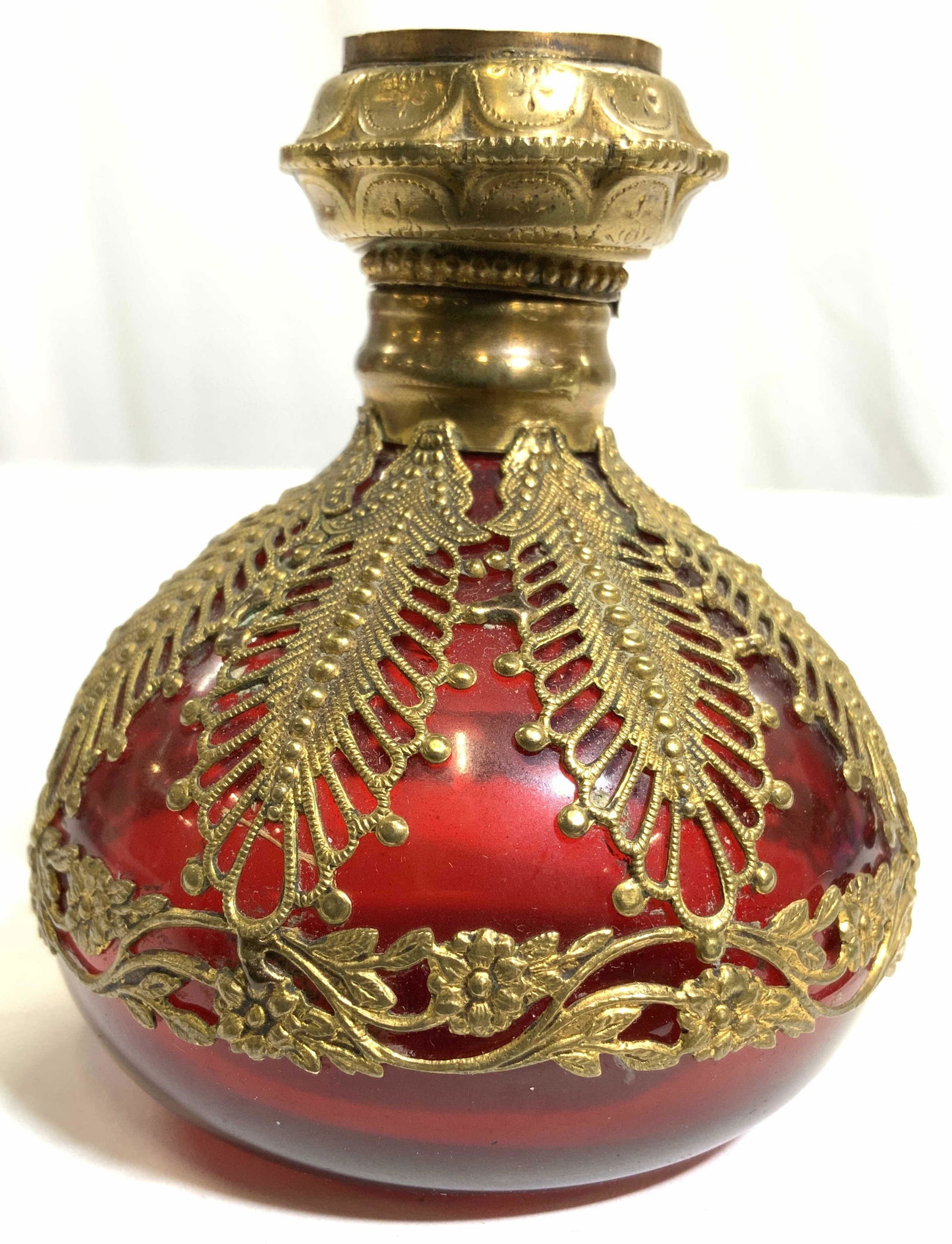 Vintage Ornate Art Glass Snuff Bottle: Snuff bottle is red with ornate gold toned detail. Stopper has image of village on top. Piece is vintage possibly antique. Piece measures approx 3.25 inches tall 2.75 inches wide. Snuff bottle, Art gl