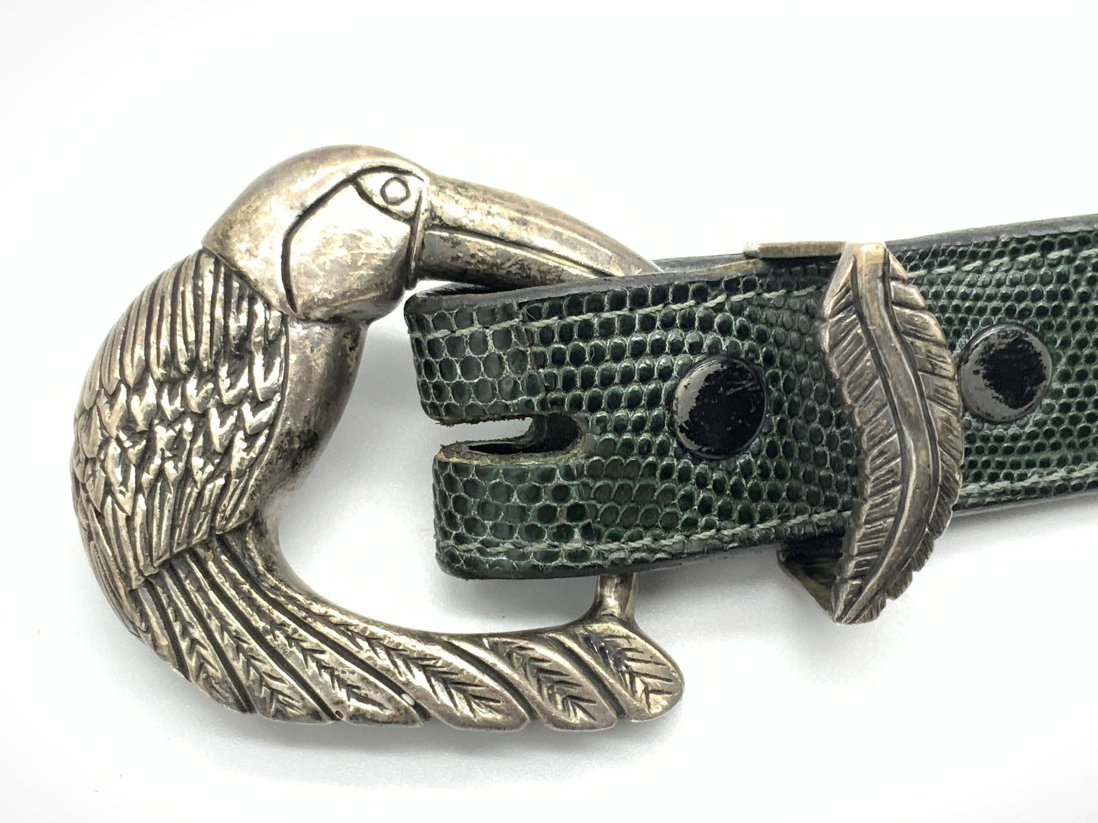 V.M. Signed Sterling Silver Leather Fashion Belt: Vintage leather fashion belt, made of green toned leather with a reptile skin texture and a black underside. Belt buckle resembles a toucan. Interior of toucan is etched with Kokopelli Designs by V.M.