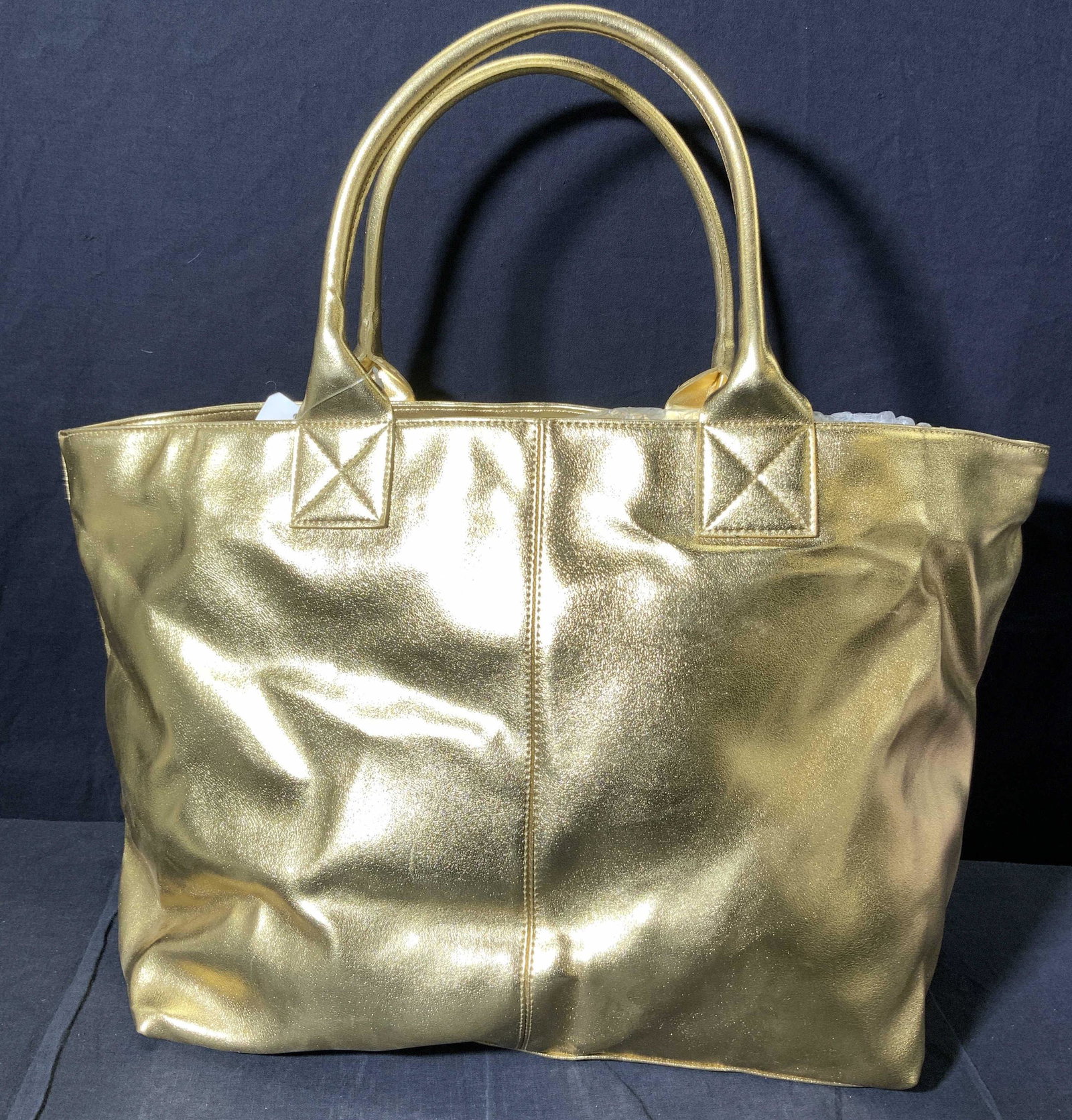 GAP Foil Leatherette Tote Bag Gold Toned: Tote is gold toned in the style of foil leather. Piece has strap on each side. Tote measures approx 18.5 inches tall & wide when full. Bag, Tote bag, gap bag, leather style bag, foil leather style bag