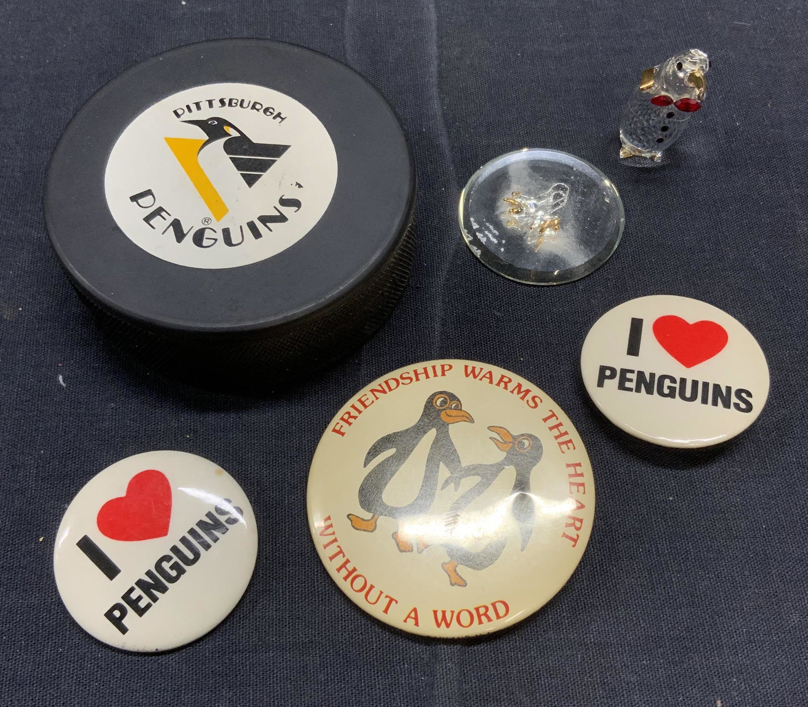 Pittsburg Penguins Memorabilia Lot: Pittsburg Penguins Memorabilia Lot, includes 1 puck, 3 pins, and a small glass Penguin figurine, which needs repair. Puck measures approx 3 inches wide. Penguins, Pittsburg penguins, sports memorabili