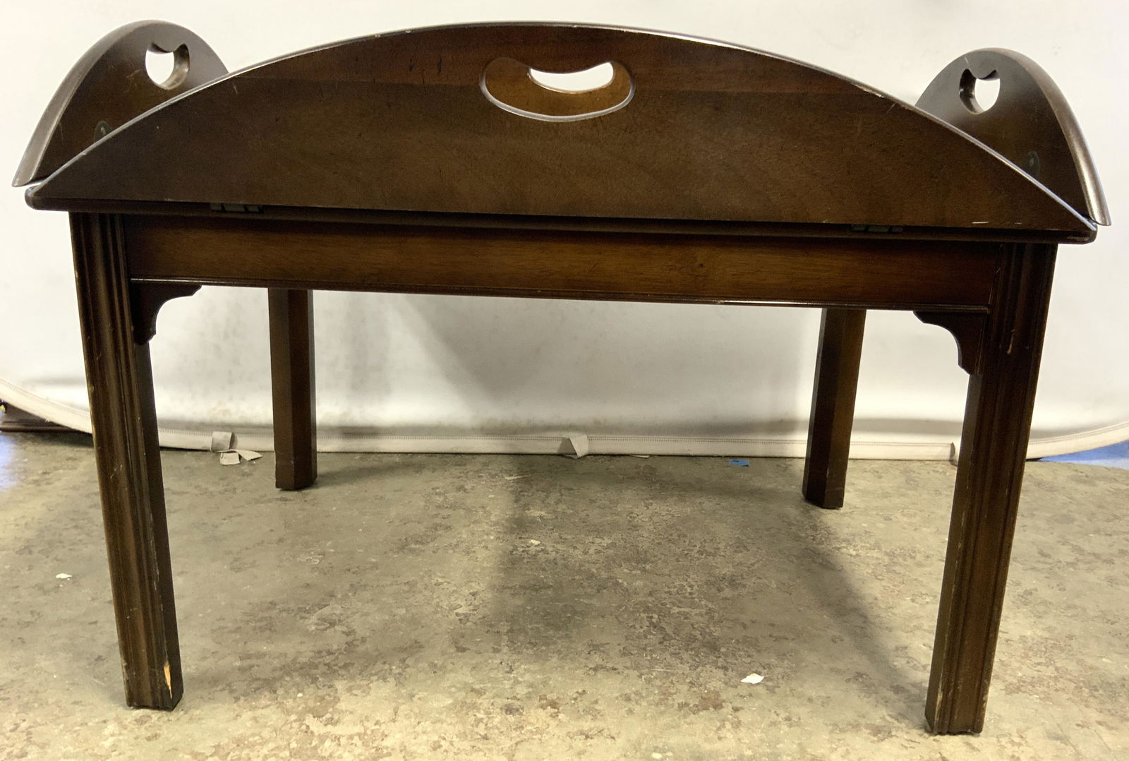 Antique Wooden Butlers Tray Table: Tray table is vintage possibly antique. Piece is brown toned and wooden. Butlers table has 4 leafs each with kidney bean shaped pierced handles. When leafs are fully open, table top becomes oval shape