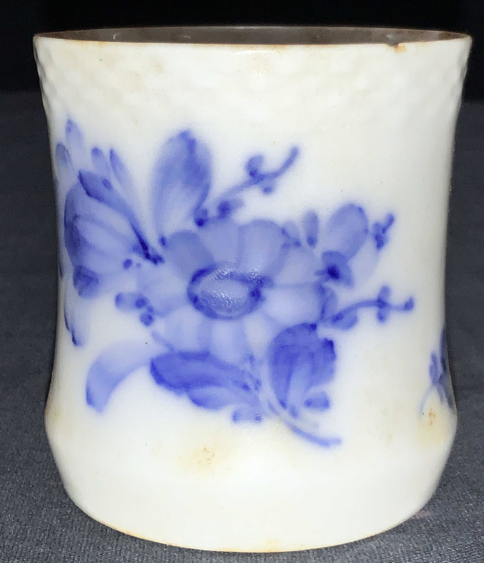 ROYAL COPENHAGEN Porcelain Cup: A white porcelain cup with blue flower motifs on the exteriors. Marked on underside Royal Copenhagen Denmark, 10, 8253. Approx 2.75 inches tall. Needs cleaning, with minor chips on rims. Royal Copenha