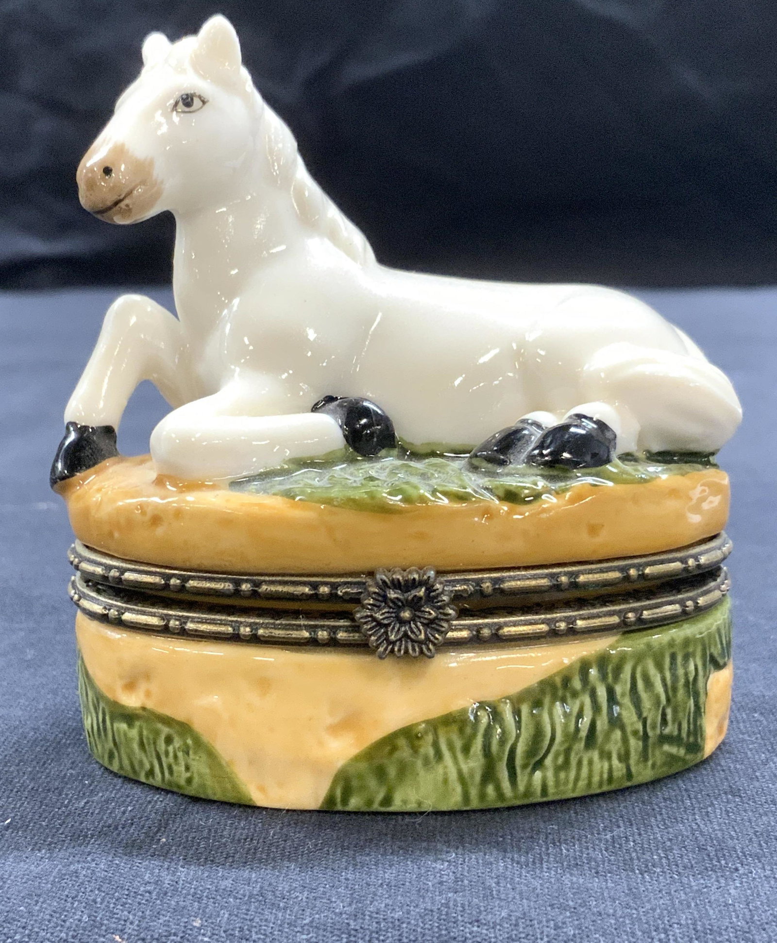 White Horse Porcelain Pill Box: White Horse Porcelain Pill Box, lid has sculptural white horse attached, box base has grass and dirt motif, push to open ornate metal clasp, measures approx 3 x 3 in., comes with miniature horse figur