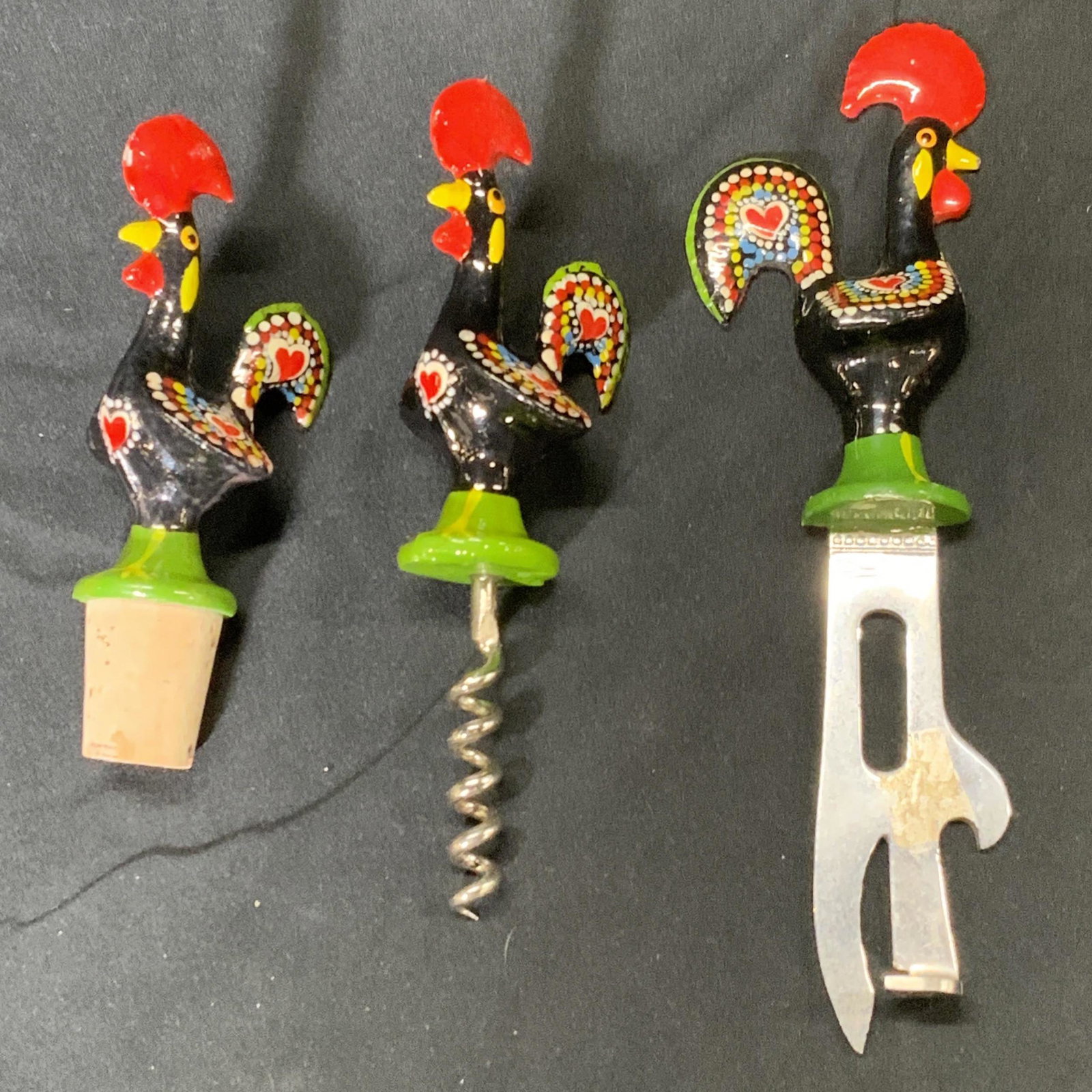 Lot 3 XONI Portuguese Rooster Wine Accessories: Lot of 3 hand painted aluminum Portuguese motif rooster wine accessories. One wine stopper featuring a brightly painted rooster, measure approx. 4.5 inches total length, 1.5 inches at widest point. On