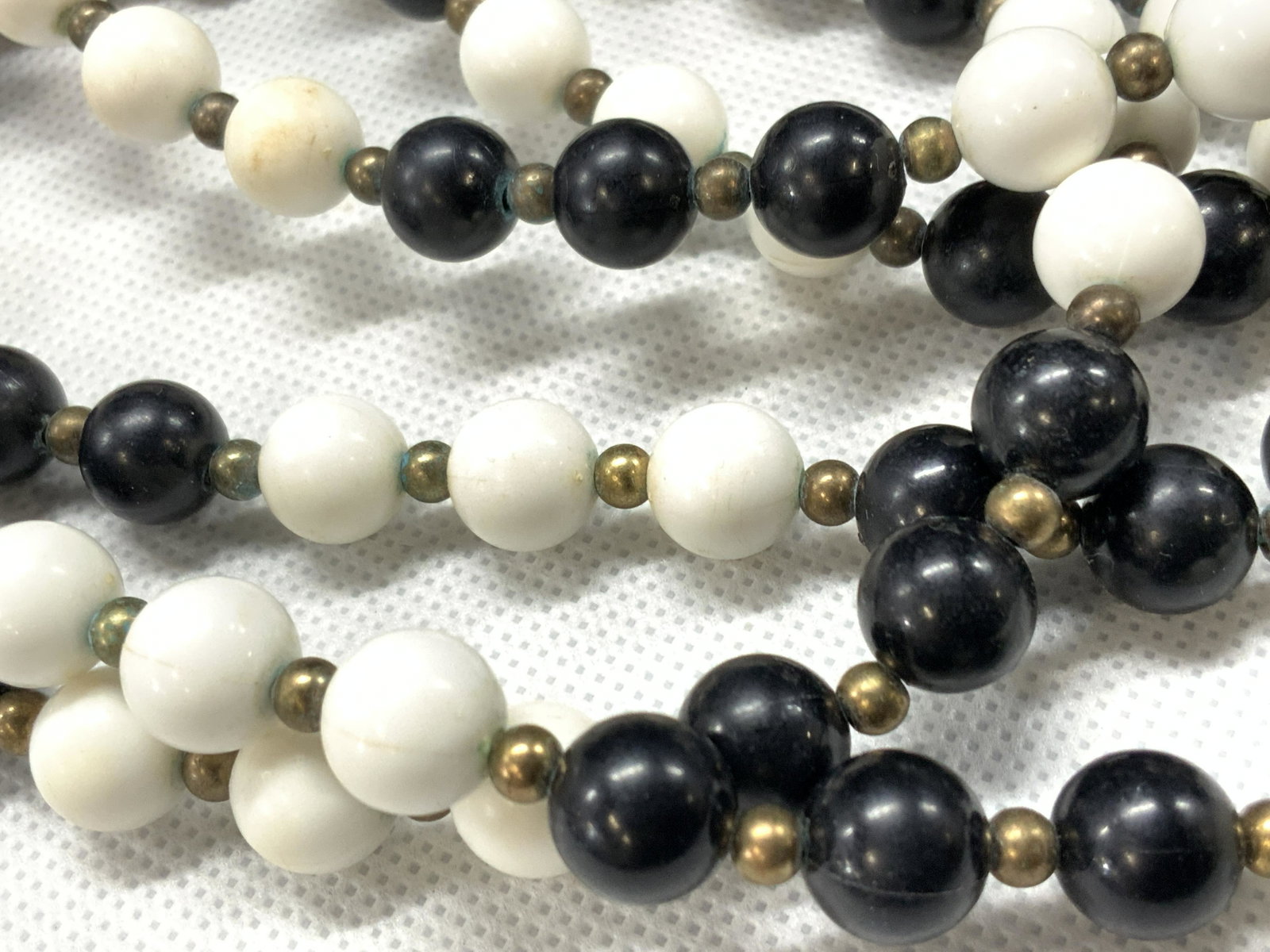 Black & White Costume Rope Necklace: Rope length necklace with black and white resin polished beads with bronze spacer beads. Approximately 52 inches long. Minor wearing to beads and clasps. Vintage rope necklace, black and white beaded 