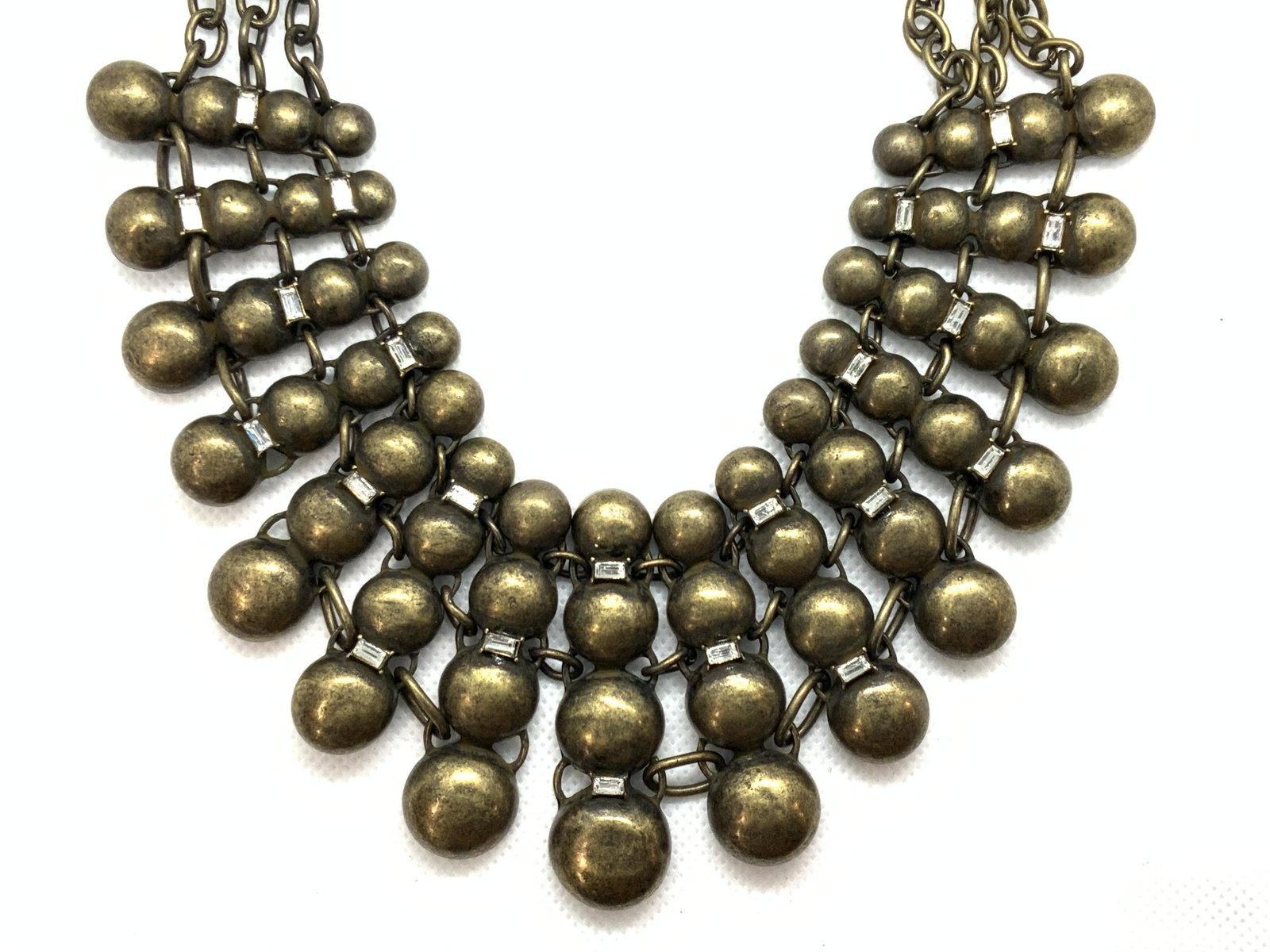 R.J.Graziano Signed Bib Necklace: A bib necklace of circular indented segments, connected with emerald cut gems in between. Marked R.G.J on necklace, and comes with original tag marked R.J.Graziano. Approximately 14 inches long. R.j.G