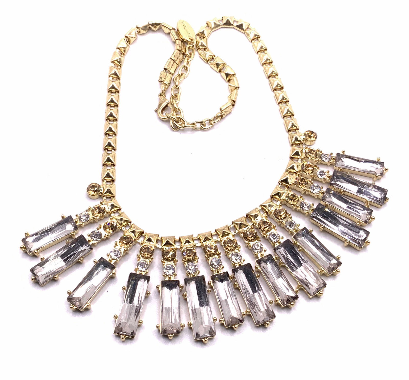 CARA NEW YORK Crystal Burst Bib Necklace, Jewelry: A gold tone metal necklace adorned with a faceted crystal burst style bib. Charm adjacent to lobster claw clasp closure reads CARA NEW YORK. Necklace length approx 19.5 in. Adjustable length. Surface 
