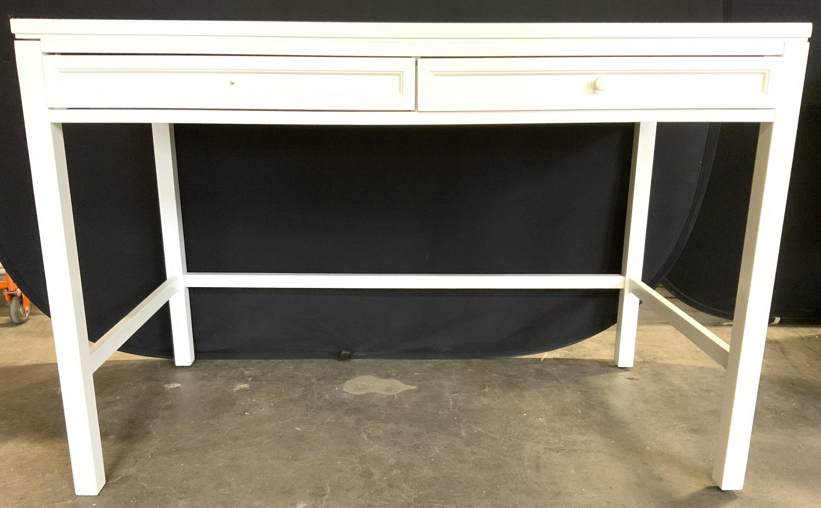 Two Drawer Work Table In Picket Fence White: Work table is in picket Fence white. Piece has 2 drawers one with knob style handles. Table legs have stretchers in between. Piece has metal legs. Measures approx 54.5 inches long 36.5 inches tall 28 