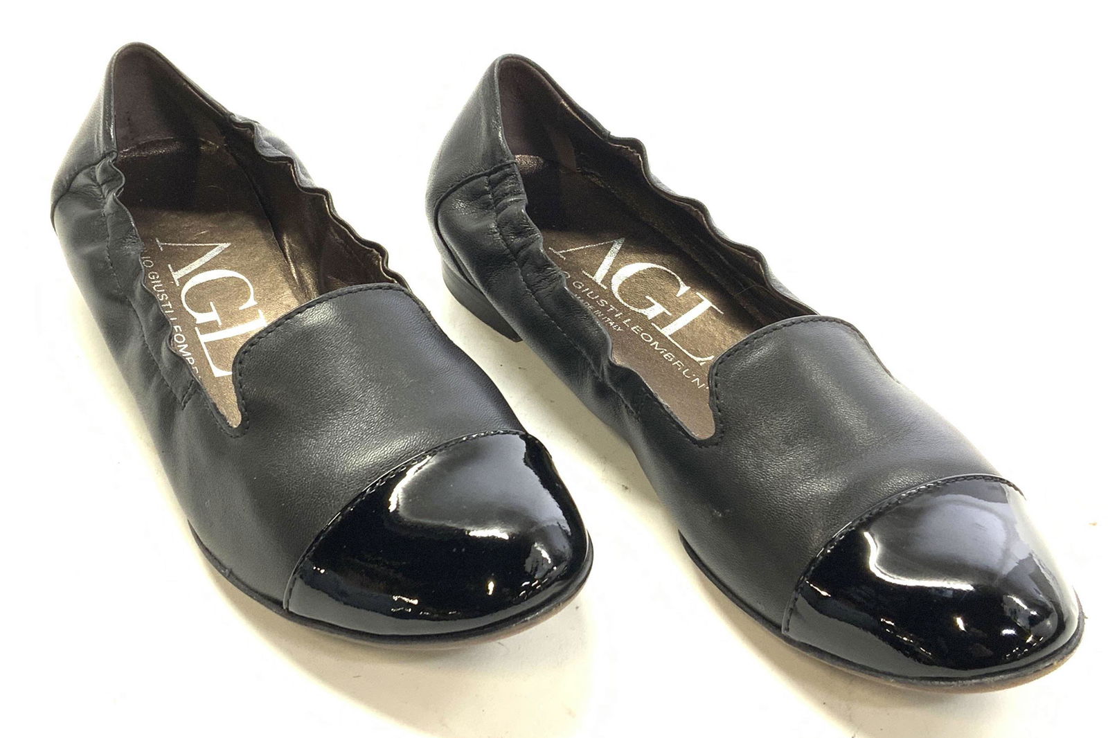 AGL Black Leather Slip On Loafers, ITALY: Signed Italian designer AGL, ATTILIO GIUSTI LEOMBRUNI soft hand black leather slip on loafers with black patent leather detail on toe. Design number N558362 printed on inside, marked size 37. Made in