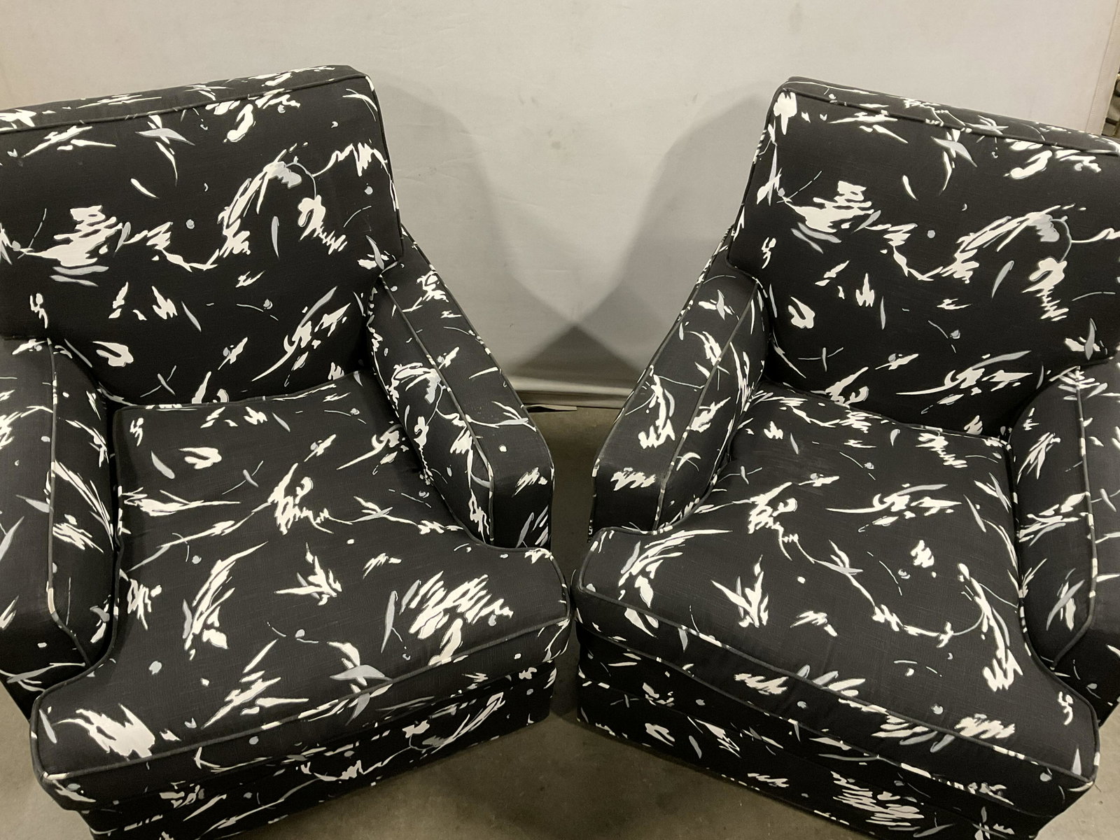 B&W Wheeled Lounge Chairs: Pair of funky Black and white lounge chairs. Both pieces have caster wheels for easy moving. Removable bottom cushion. Abstract details to fabric. Measures approx 32H x 35D x 30W inches. Retro furnitu