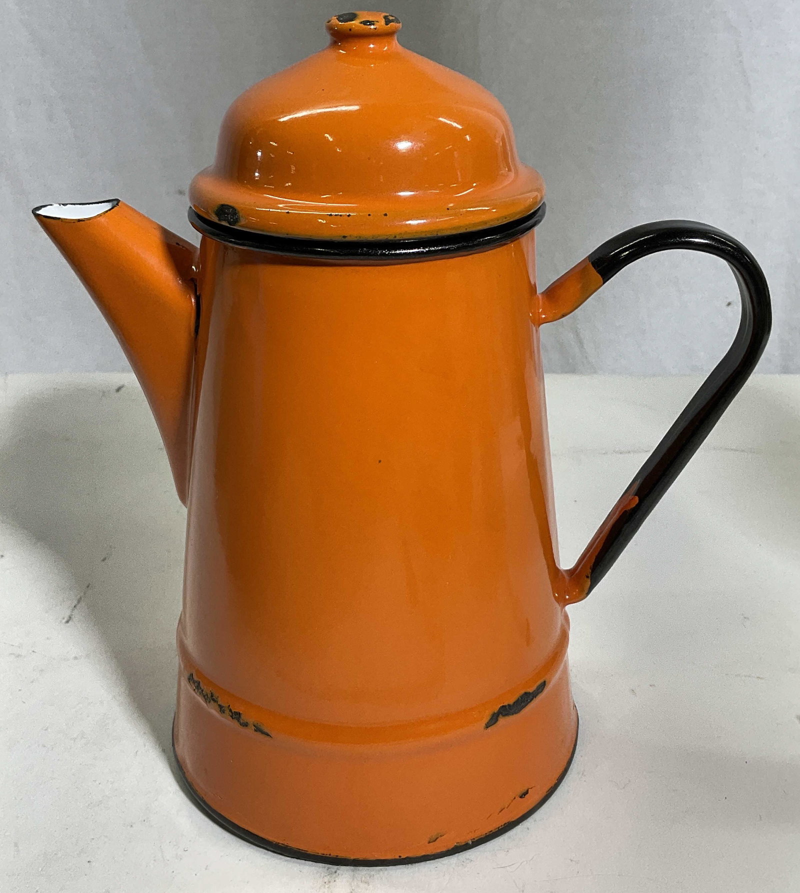 Orange Enamel Teapot: Tangerine colored enamel tea pot. Measures approx 8.5H x 7.5W inches. Wear to piece and chipping to enamel. Bottom reads Made in Poland. Enamel, teapot, kitchenalia, kitchenware, earthenware, orange t