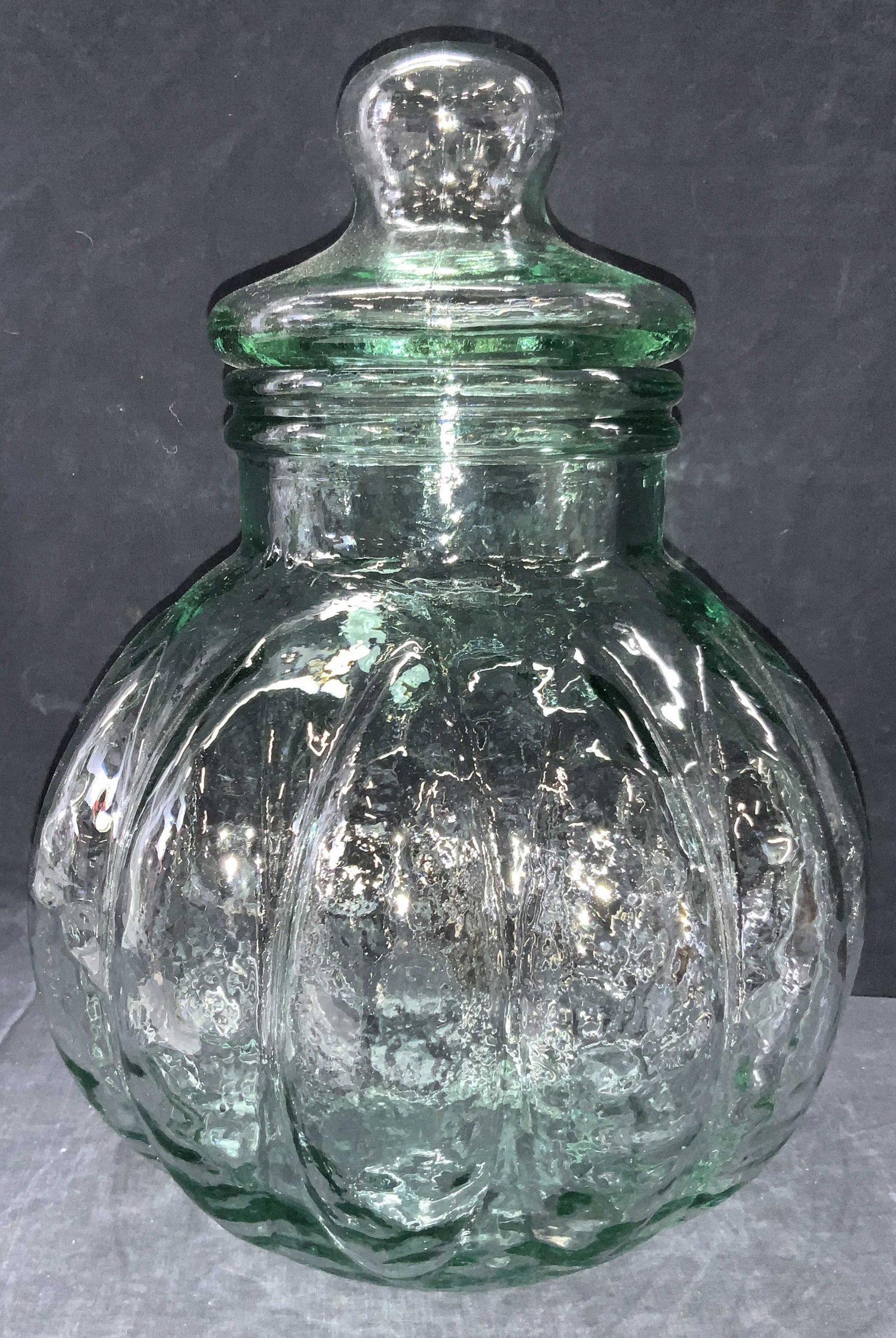 Vintage Green Toned Glass Vessel W Lid: A green toned vessel with lid. Body is bulbous with sections extending outward. Approximately 15 inches tall. Vintage glass vessel, vintage green toned glass, vintage glass jar, glass jar, candy dish,