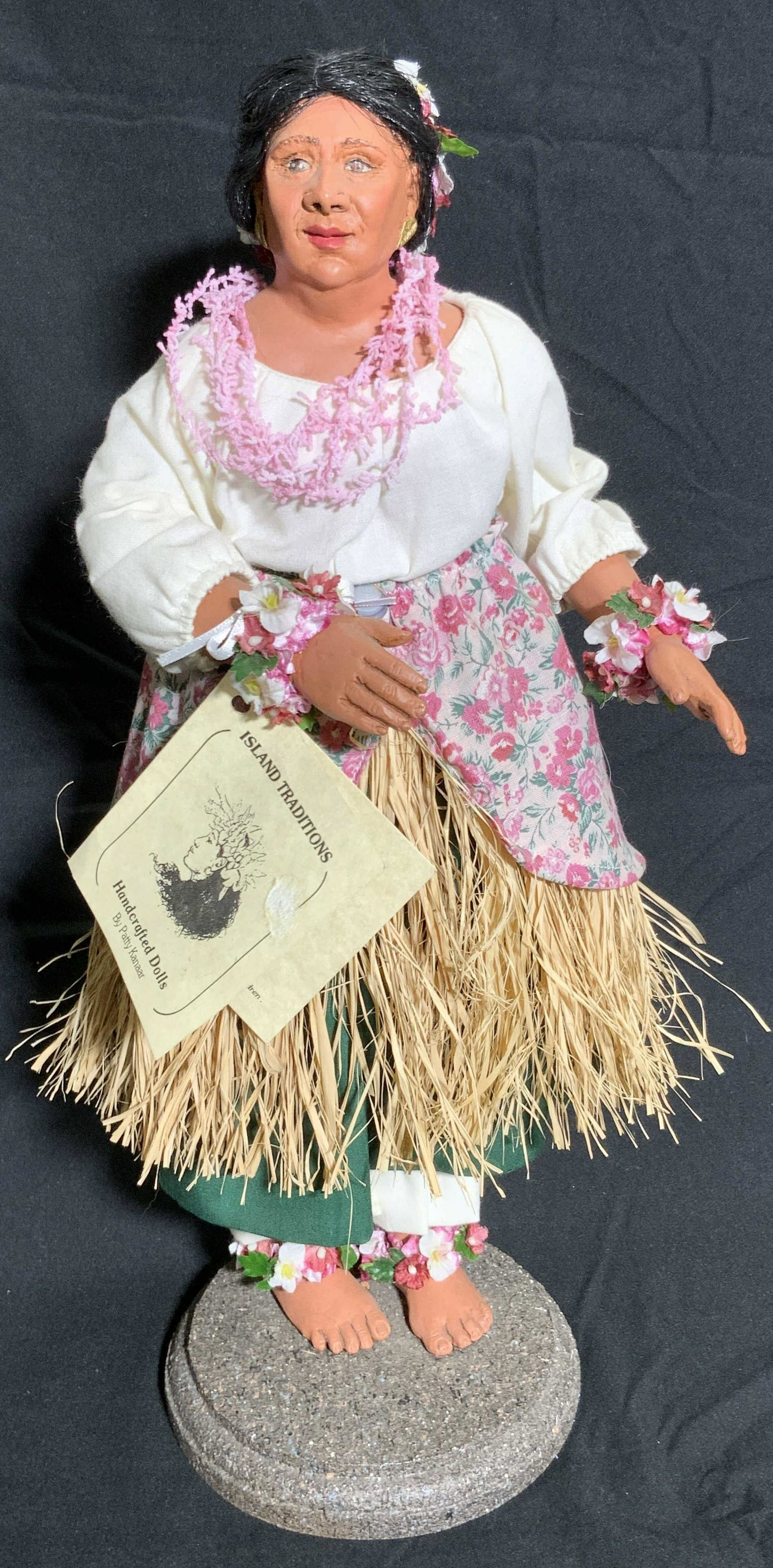 ISLAND TRADITIONS Handcrafted Doll by Patty Kanaar: A resinous handcrafted doll titled Auntys Hula, wearing a traditional costume. Tag reads ISLAND TRADITIONS Handcrafted Dolls by Patty Kanaar, issued on 9/20/97, Hei Mana Creations 1991, handcrafted fr