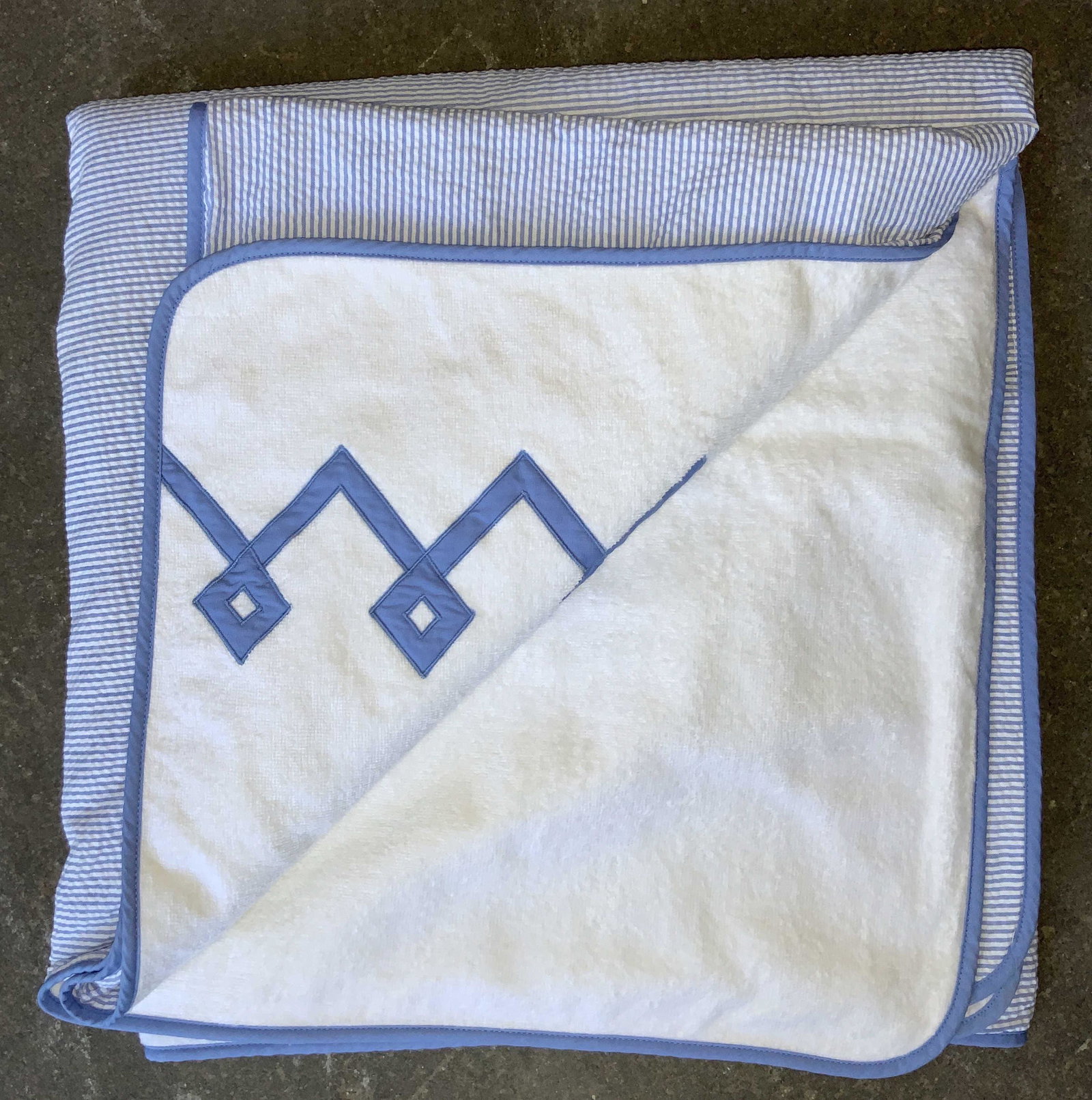 LEONTINE LINENS Bergdorf Goodman Linen Lap Blanket: Lap blanket with white underside, with reverse side being blue and white striped. Underside is stitched with blue cross knot pattern. Marked on tag Leontine Linens Bergdorf Goodman. Approximately 68 i