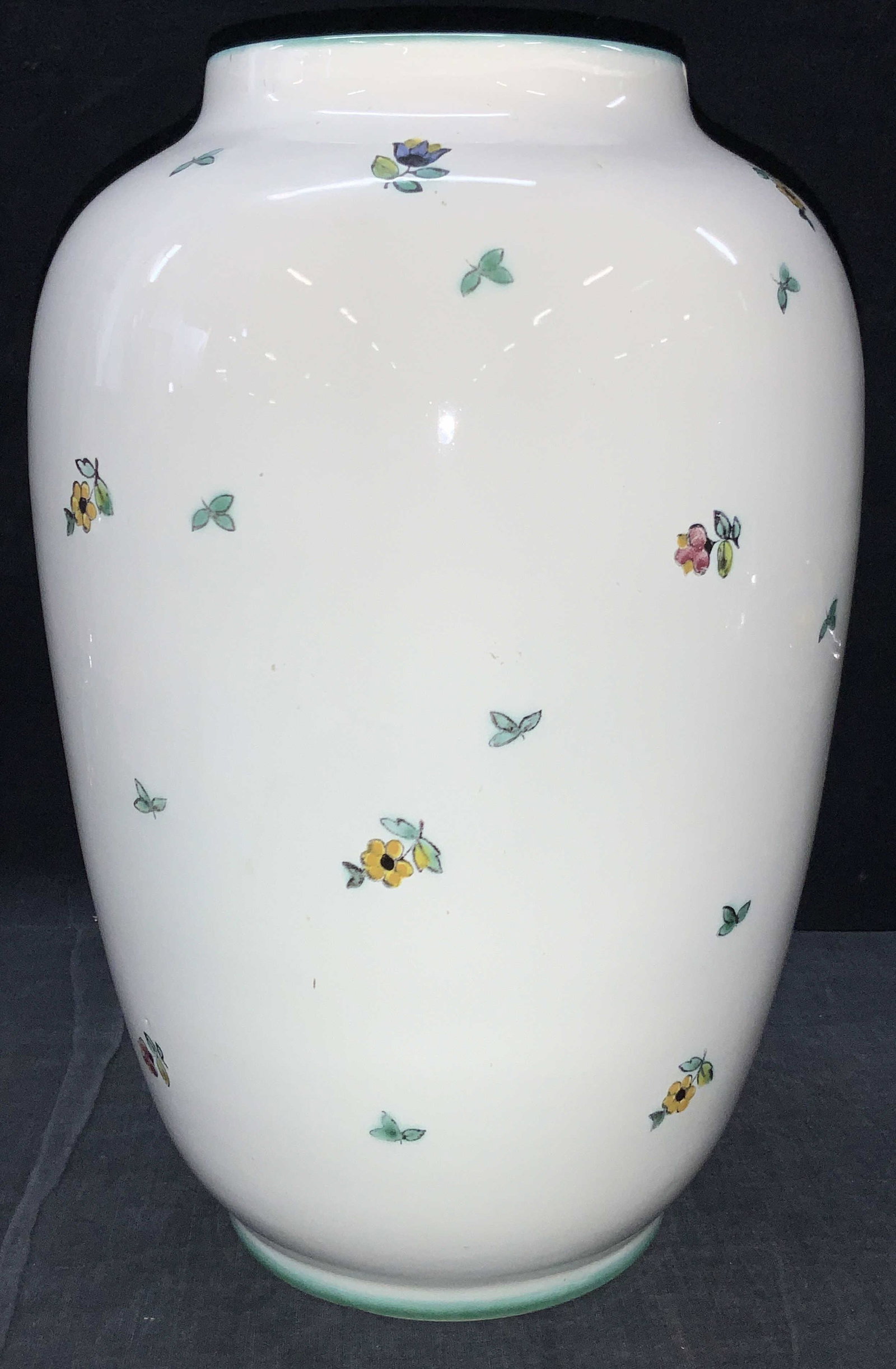 GMUNDNER KERAMIK porcelain Vase: White porcelain vessel with painted flowers on exterior in teal toned paint and purples and yellows. Teal painted rim. Marked on underside GMUNDNER KERAMIK, Austria. Approximately 13 inches tall. Evid