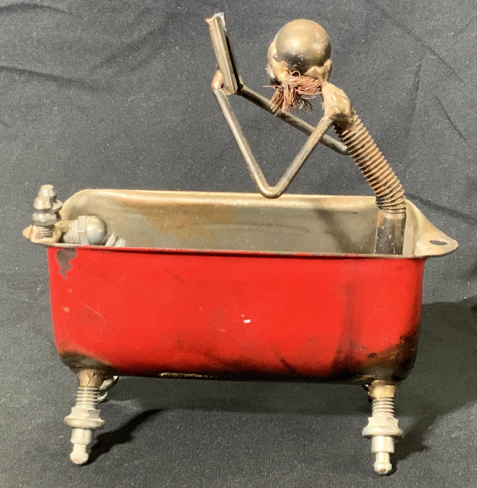 Vintage Handmade Metal Man In Bathtub Sculpture: A vintage handmade sculpture depicting a nude man reading a book and taking a bath. Crafted from a variety of metal pieces, screws, wire, and more. Bathtub is red, metal is primarily a silver tone. Me