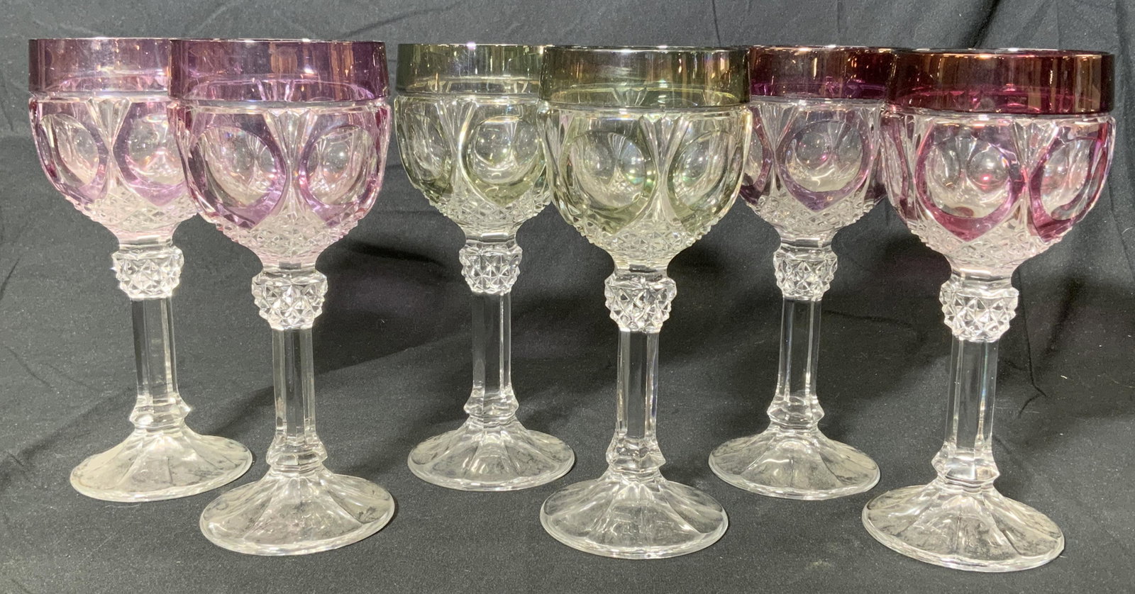 Lot 6 Vintage Colored Wine Glasses: Lot of 6 matching colored wine glasses, 2 maroon, 2 purple, 2 green. Each glass measures approx. 7.5 inches tall and 3 inches wide. Some wear to glasses consistent with use and exposure. Wine glasses,