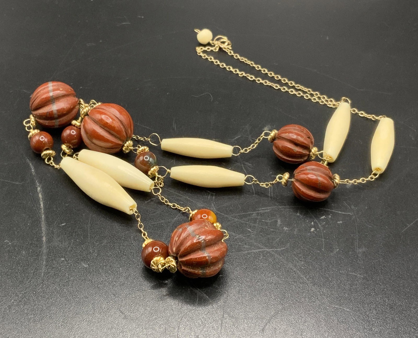 Vintage 14K Gold Beaded Bone Necklace: Vintage 14K gold cable chain necklace with carved, possibly bone, white oblong beads and round rust colored composite beads. Trademarked on spring ring clasp 14K XL. Necklace length approx. 25 inches 