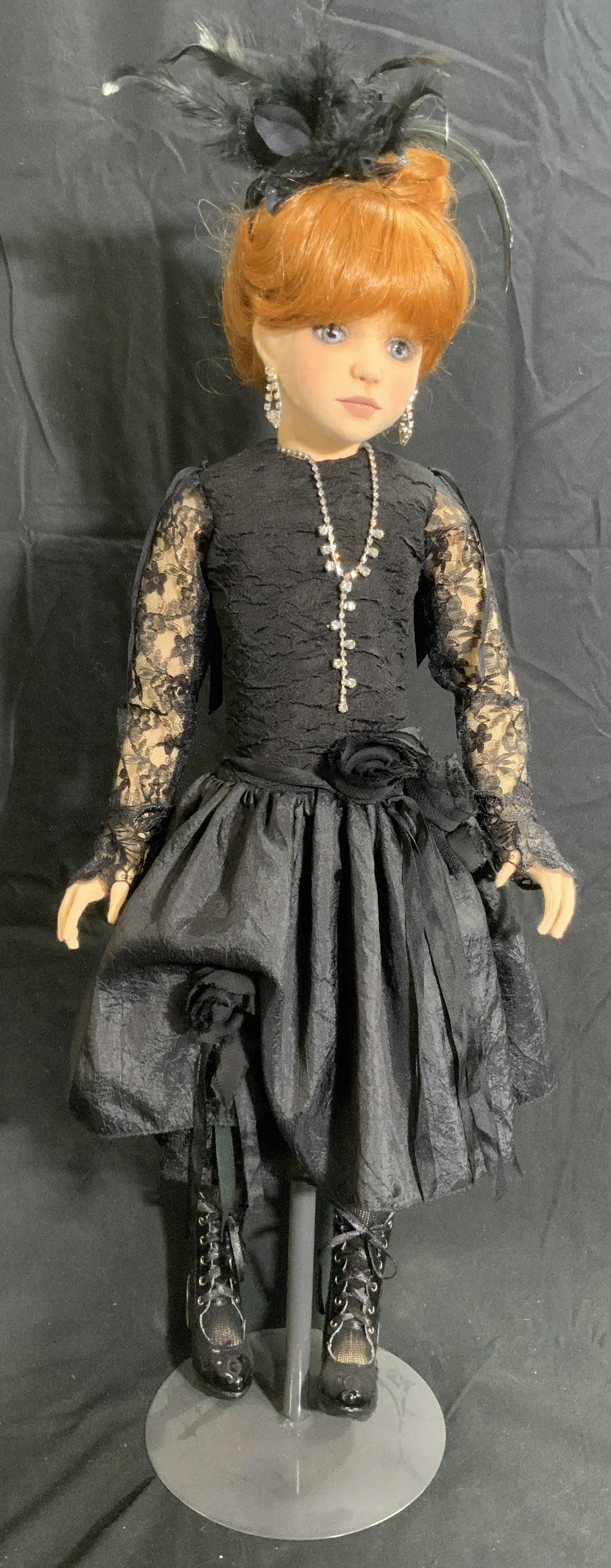 Female Doll W/ Black Lace Dress, Metal Stand: A fabric female doll wearing a black lace accented dress and jewelry. Feathered hair piece accents her updo. Black lace up boots to her feet. Comes with a metal stand. Measures approx 24H x 9W in. Som