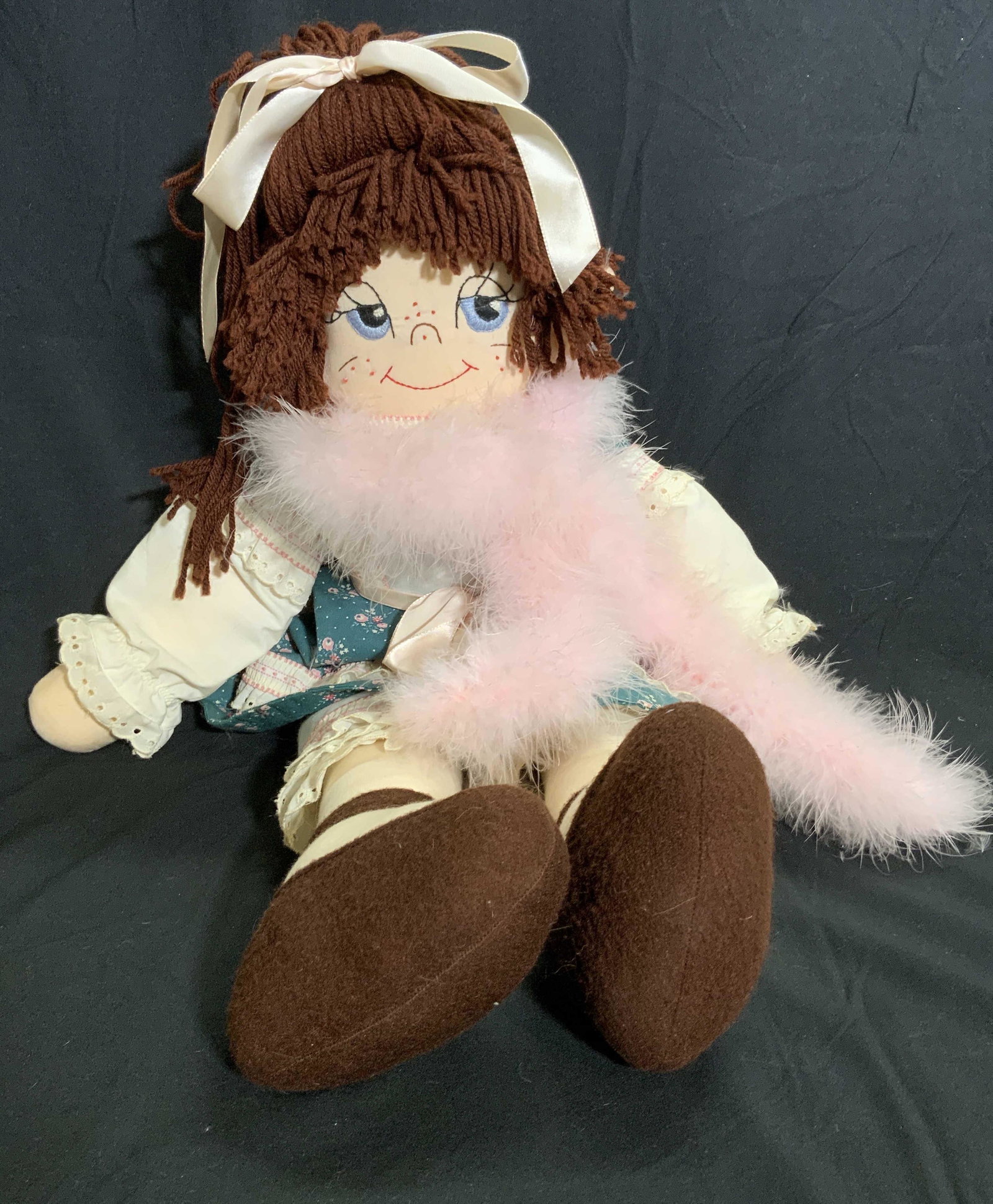 SIGNED Hand Embroidered Doll W/ Pink Boa Scarf: A doll wearing a dress and a feathered pink boa. Crafted from fabric. Embroidered facial features. Signature appears to read CORA STIEN, #6, 5-87, Jess. Measures approx 26L x 12W in. Measured at wides