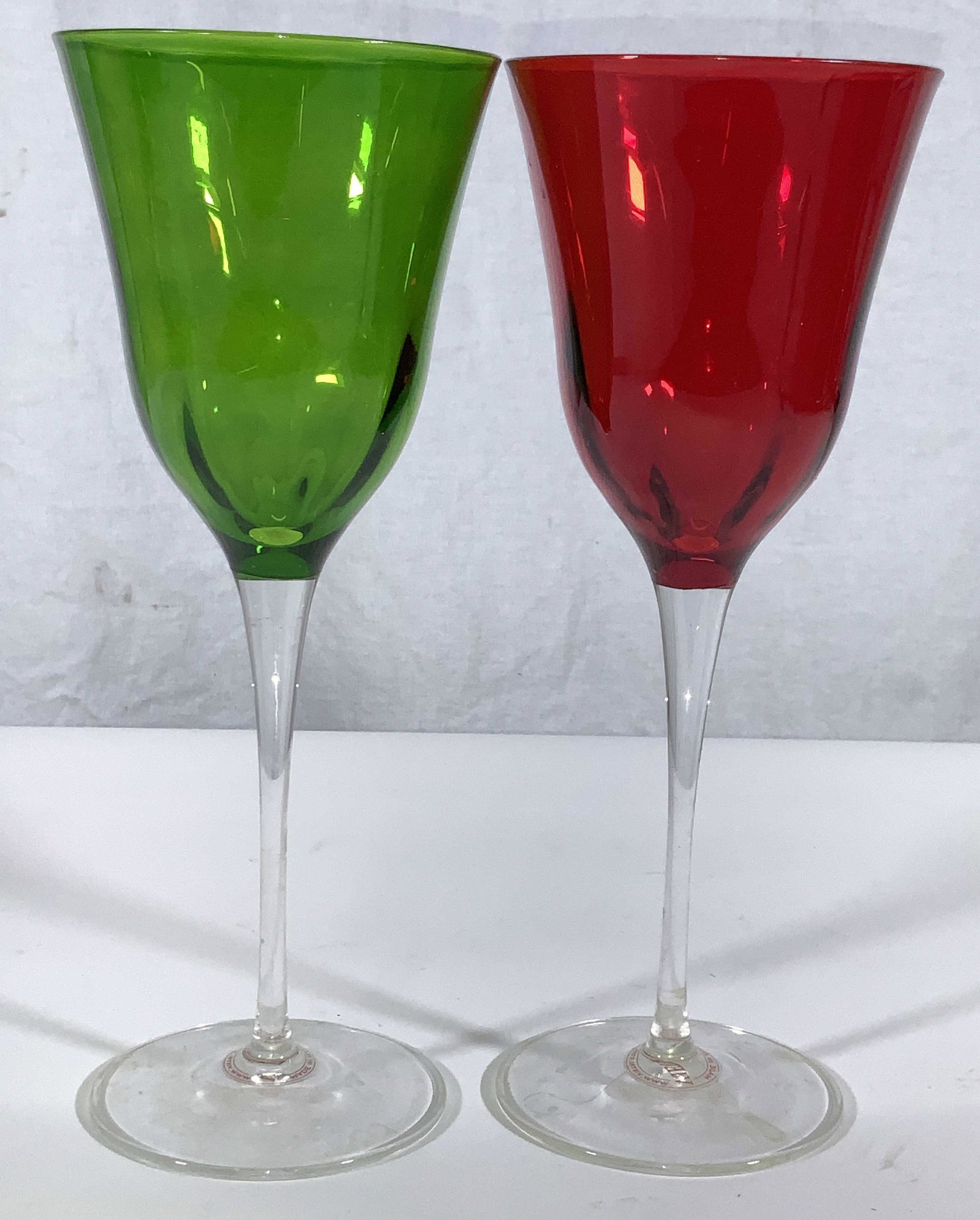 VIETRI Hand blown Colored Italian Stemware- pair: Murano wine glasses, One cranberry red, the other Green, signed VIETRI hand blown crystal stemware. Sticker label on bottom of peach glass. Tall stem, each glass measures 9 x 3.5 in. Made in Italy. Si