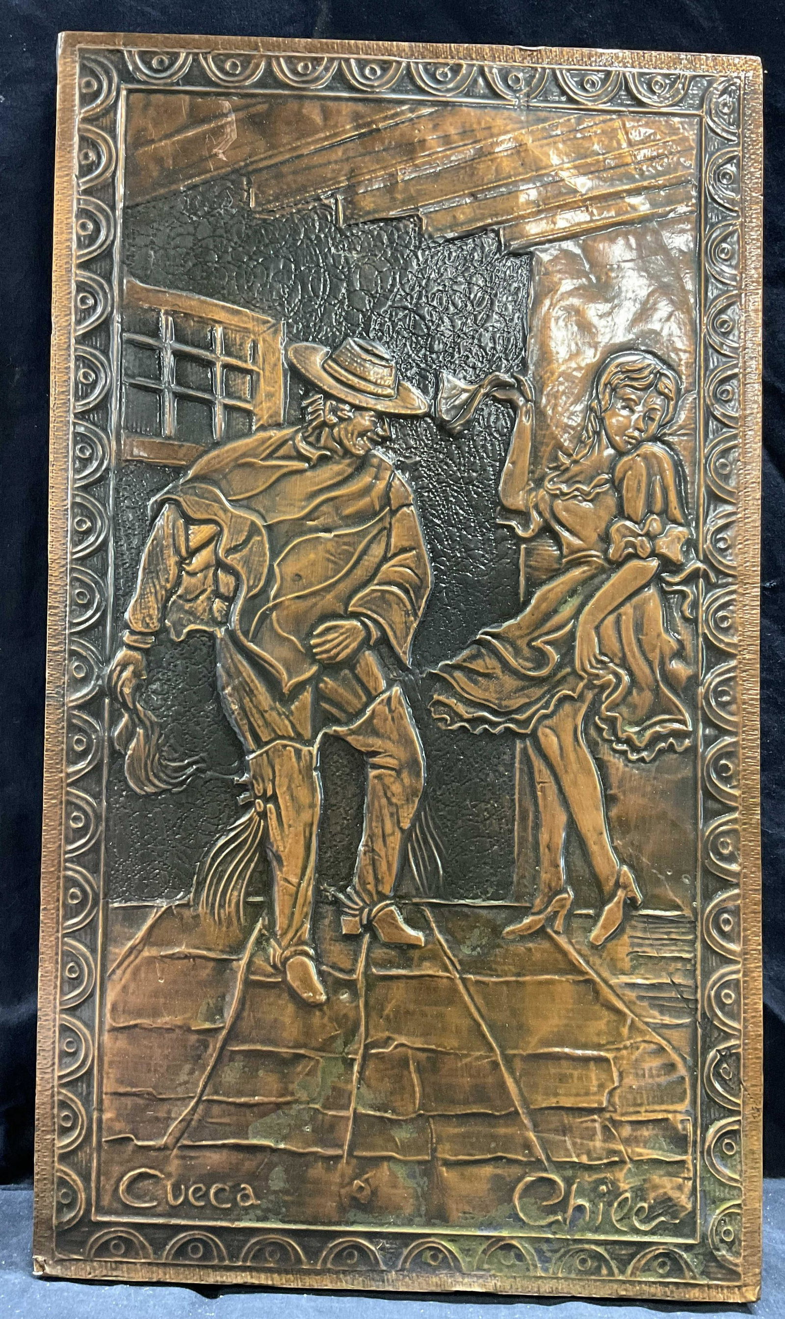 Chilean Hammered Copper Relief Sculpture: Chilean Hammered Copper Relief Sculpture, mounted on masonite, inscriptions read Cueca, Chile, subject a woman and man dancing, measures 23 1/4 x 13 1/2 inches, some losses to edge of piece, lower por