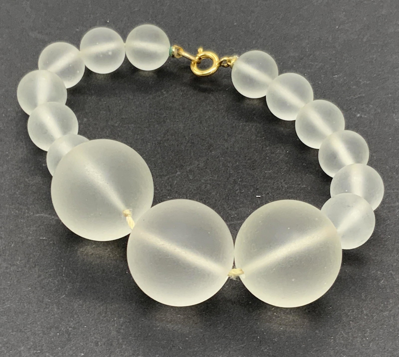 GOLD FILLED Frosted Glass Graduated Bead Bracelet: A frosted bead graduated bracelet. Beads appear to be crafted from glass. Gold filled C-spring clasp bracelet marked GF 20-12kt. Bracelet length approx. 8.5 inches. There appear to be bubbles to glass