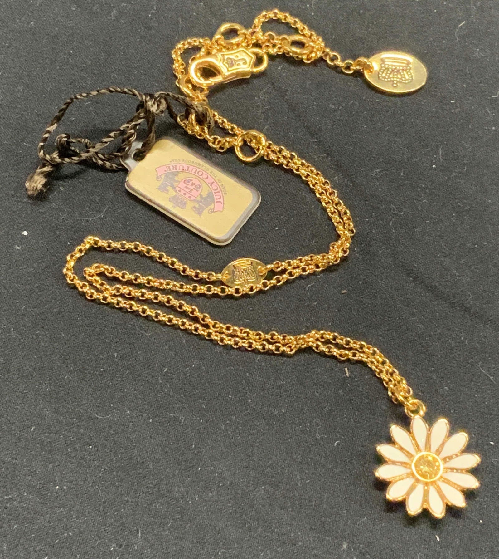 JUICY COUTURE Flowers of Romance Pendant Necklace: Juicy Couture Flower of Romance gold tone curb chain necklace with white enamel and yellow faceted crystal daisy pendant. Lobster claw clasp, signed on clasp and brand logo on necklace charm. Measures