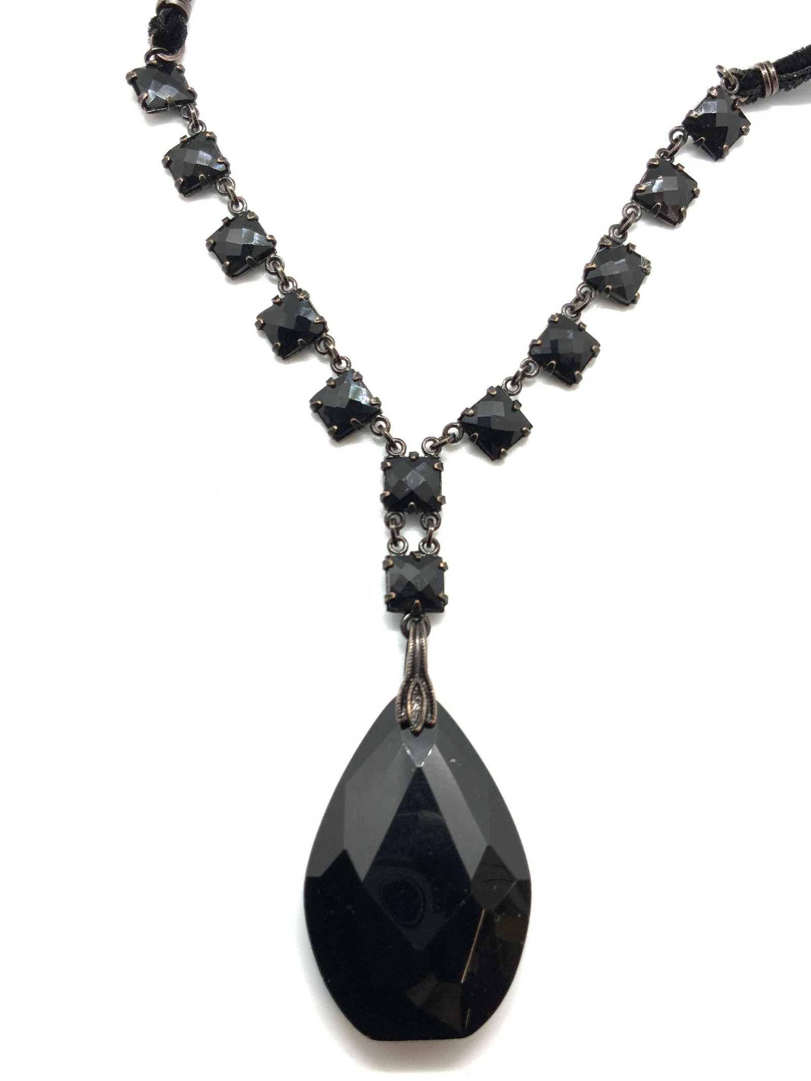 REALITIES Signed Black Cut Crystal Pendant Choker: A black corded choker necklace with faceted black glass gemstones, affixed is a tear drop shaped faceted gemstone pendant. Comes with Realities tag. Approximately 10 inches long. Marked Realities on c