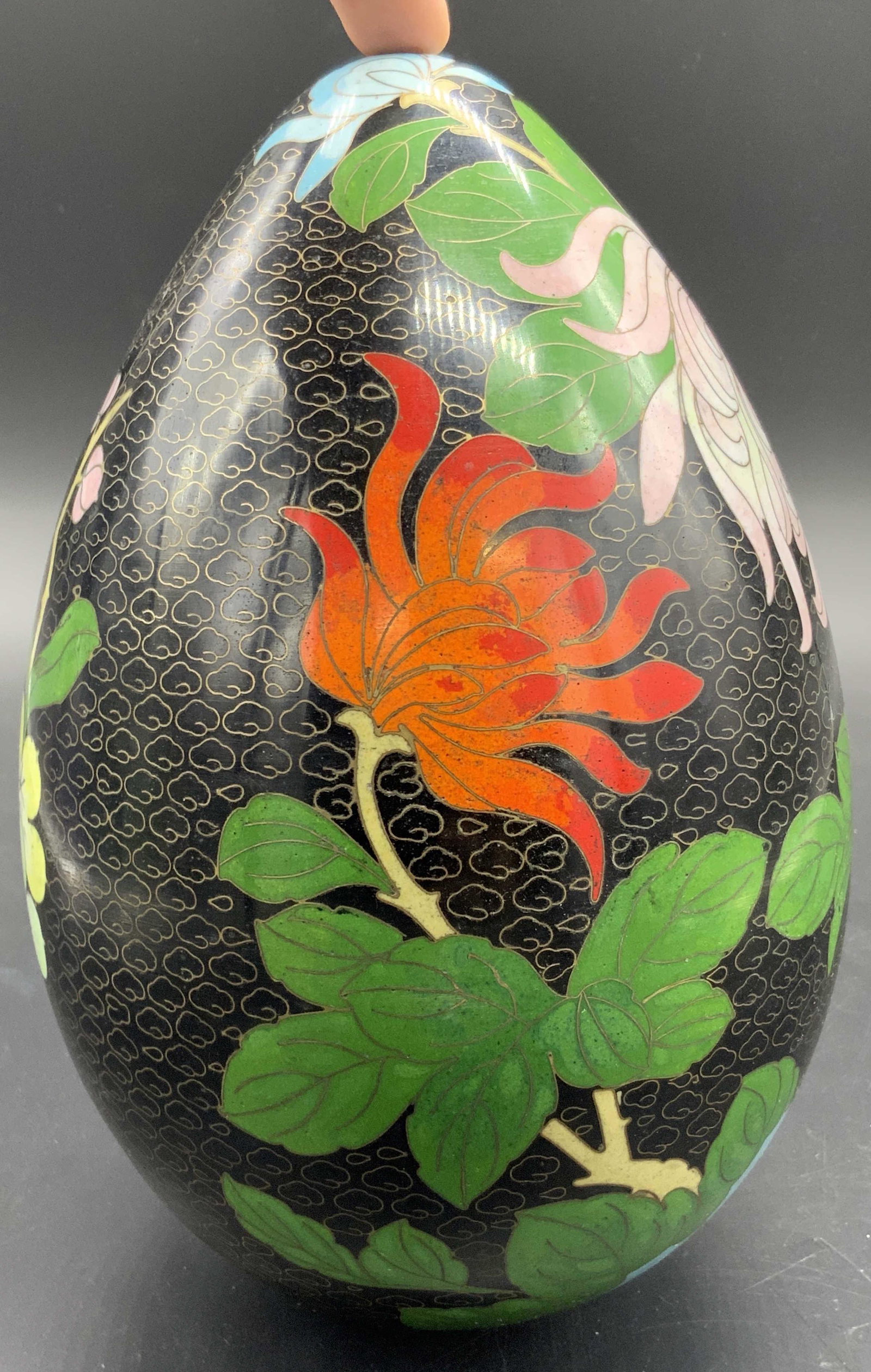 Vintage Floral& Butterfly Motif Cloisonne Egg: A vintage cloisonne egg decorated with a floral and butterfly motif. Thunder and cloud pattern throughout. Egg is mostly black with pops of pink, yellow, green, red, and blue. Drilled hole to undersid
