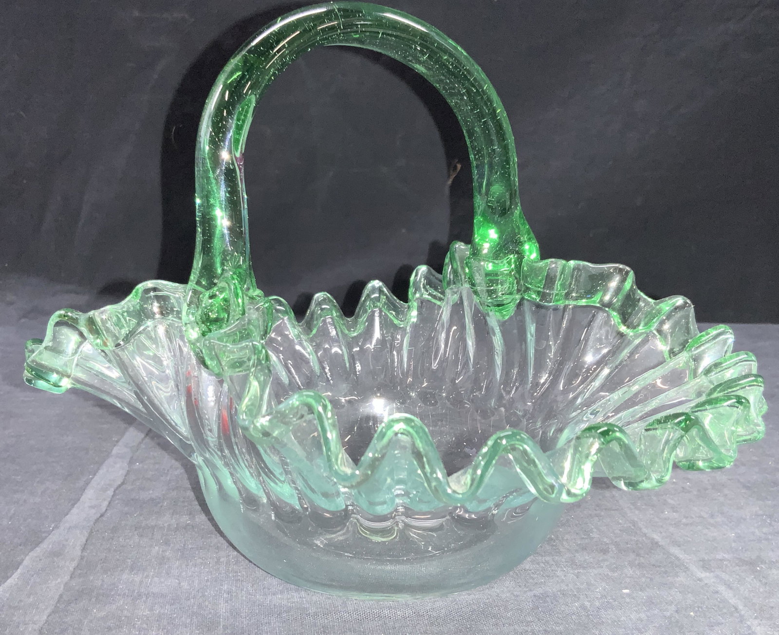 Hand Blown Green Handkerchief Style Basket: Hand blown green toned glass basket with handkerchief style rims. Pontil on underside. Approximately 7 inches tall and 9 inches wide. Property of Palm Beach, Fl Estate. Hand blown glass basket, glass 
